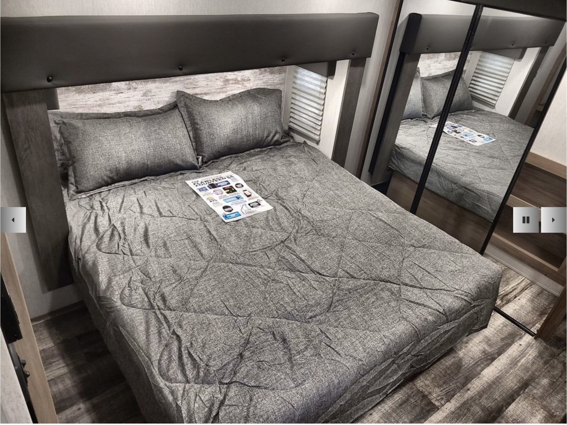 Cozy grey bed in an RV rental bedroom with a modern headboard and mirror reflection.. Forest River Cherokee Arctic Wolf Suite 3770 2024