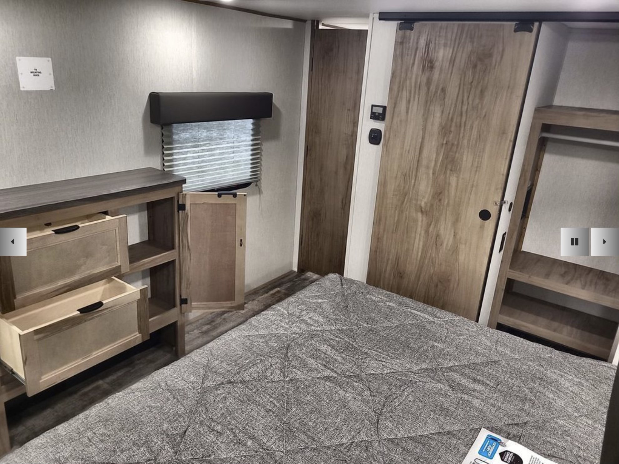 Cozy RV rental bedroom with comfy bed, pull-out storage drawers, window blinds, and a stylish sliding door.. Forest River Cherokee Arctic Wolf Suite 3770 2024