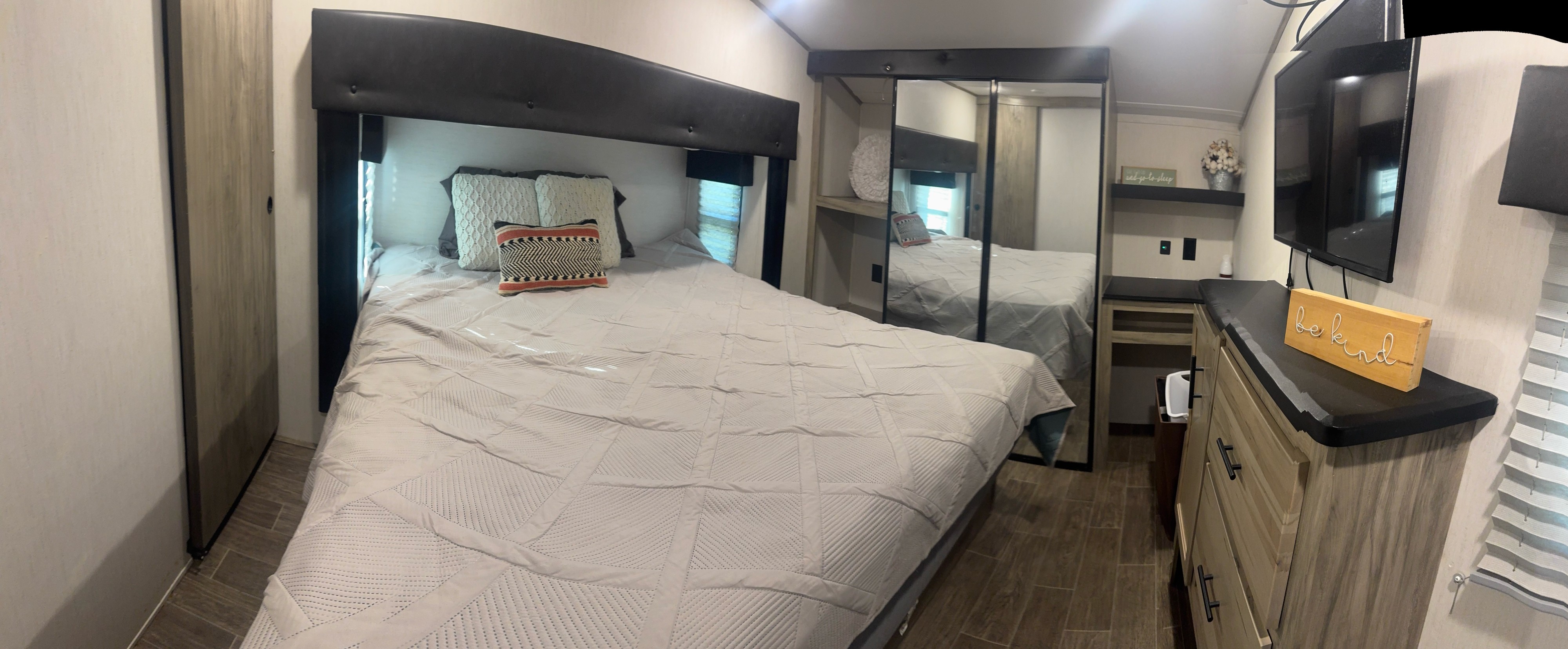 Inside a comfortable RV rental bedroom featuring a large bed, mirrored closet, and dresser with TV for cozy travels.. Arctic Fox 3660 Suite 2023
