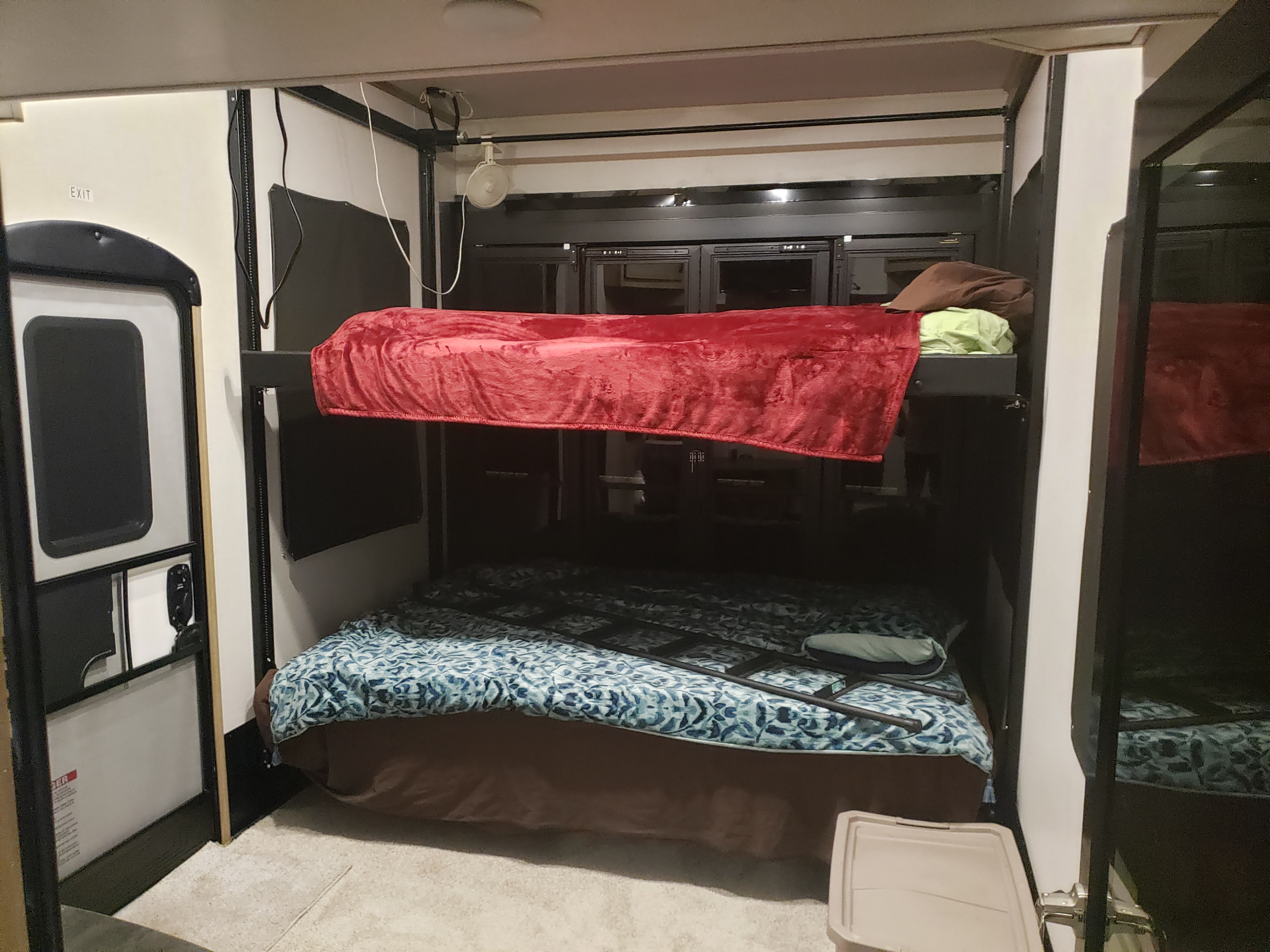 Cozy RV rental interior featuring comfortable bunk beds with colorful blankets, a ladder, and an exit door.. Keystone RV Raptor Toy Hauler 2022