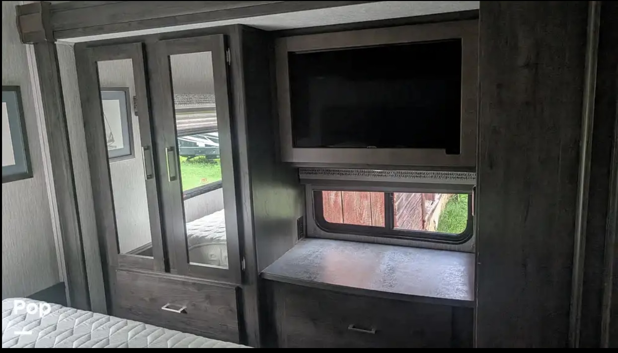 Spacious RV rental bedroom with TV, mirrored closet, and window. Ideal for comfortable travel.. PURSUIT 31BHF 2022