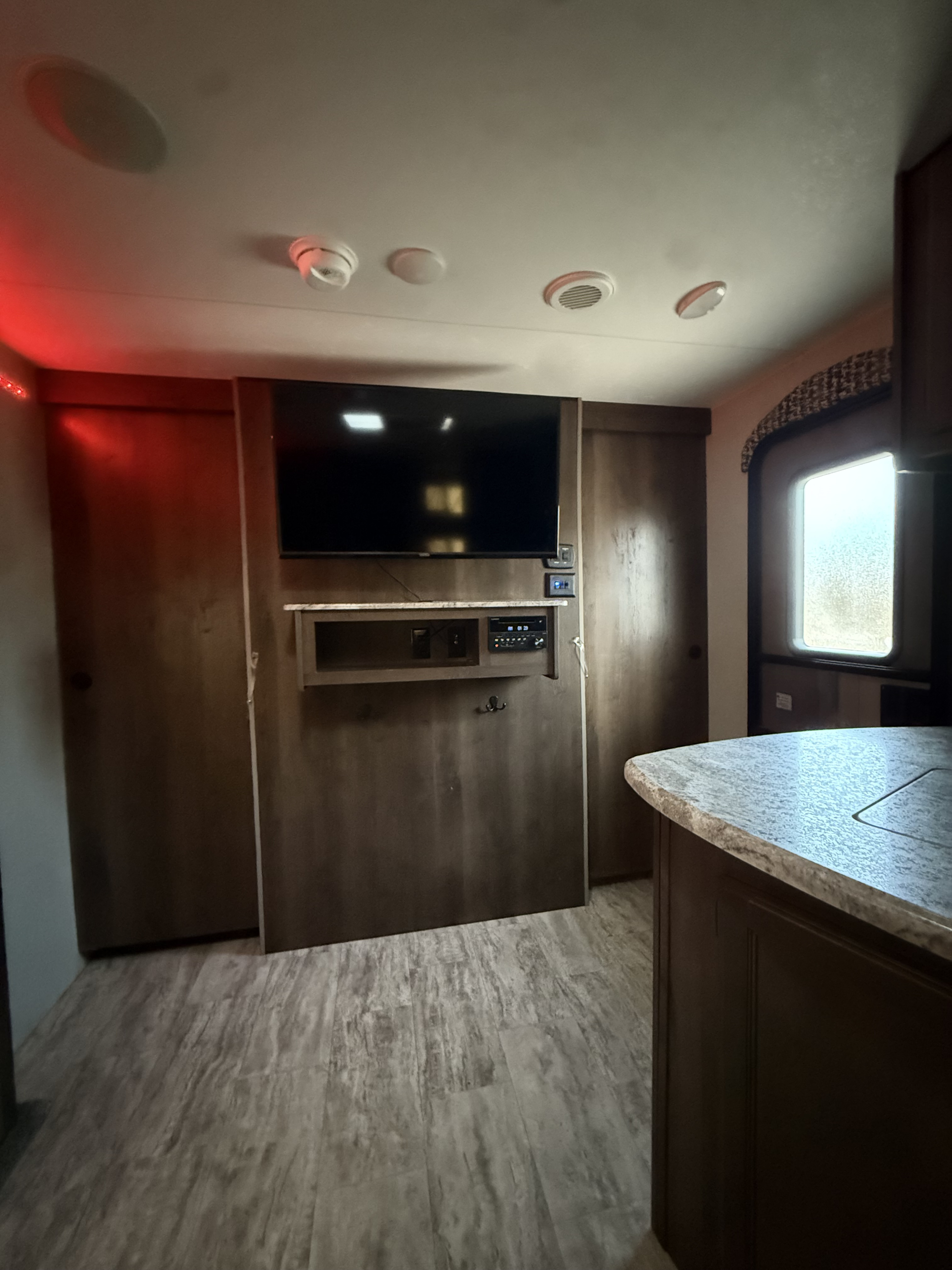 This RV rental's modern interior features a TV, entertainment unit, wall-bed, storage, and kitchen counter.. KZ connect 241 bhk 2019