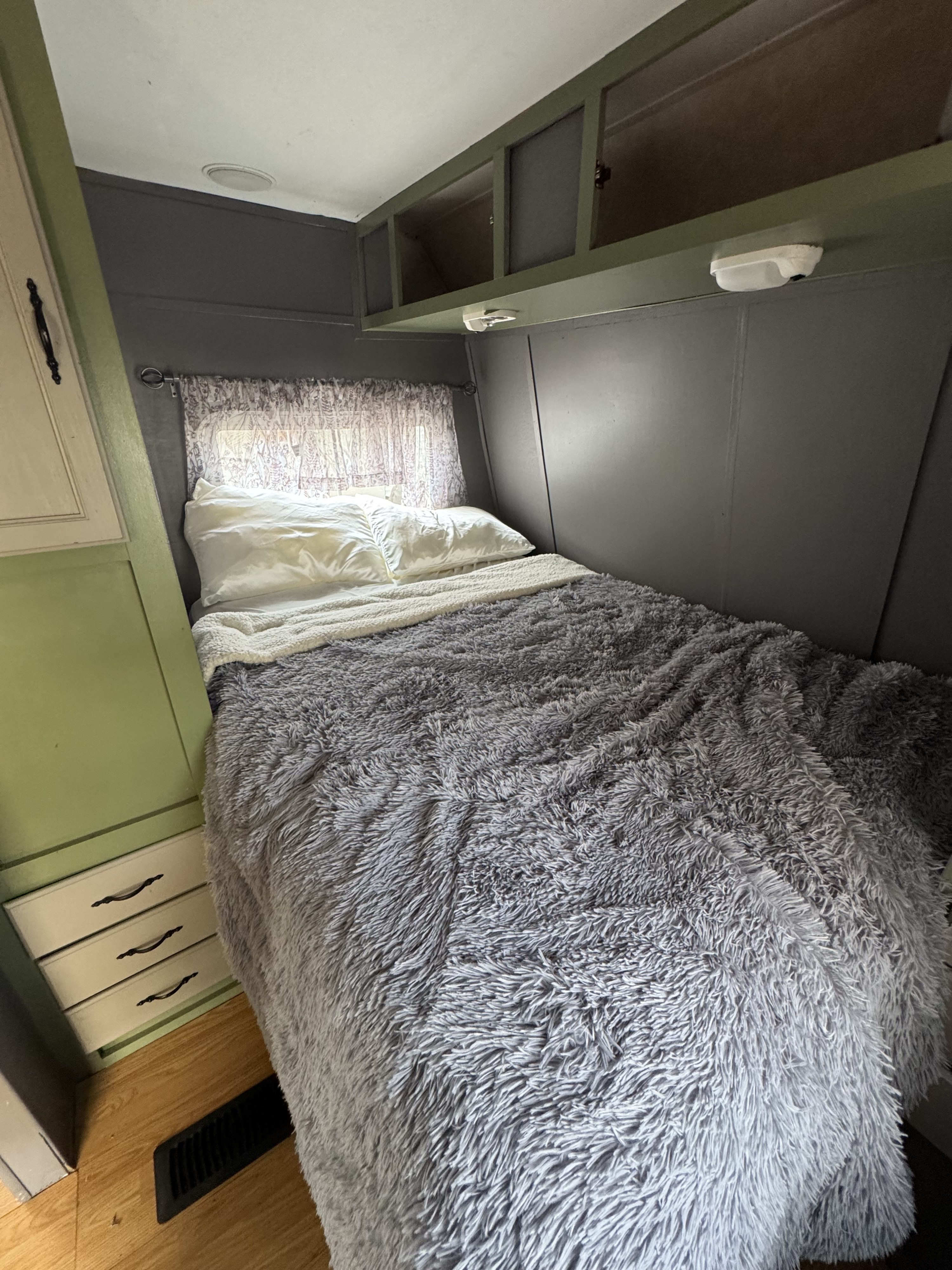 Cozy RV rental bedroom with fluffy gray bed, built-in storage, and window.. SALEM Travel Trailer 2005