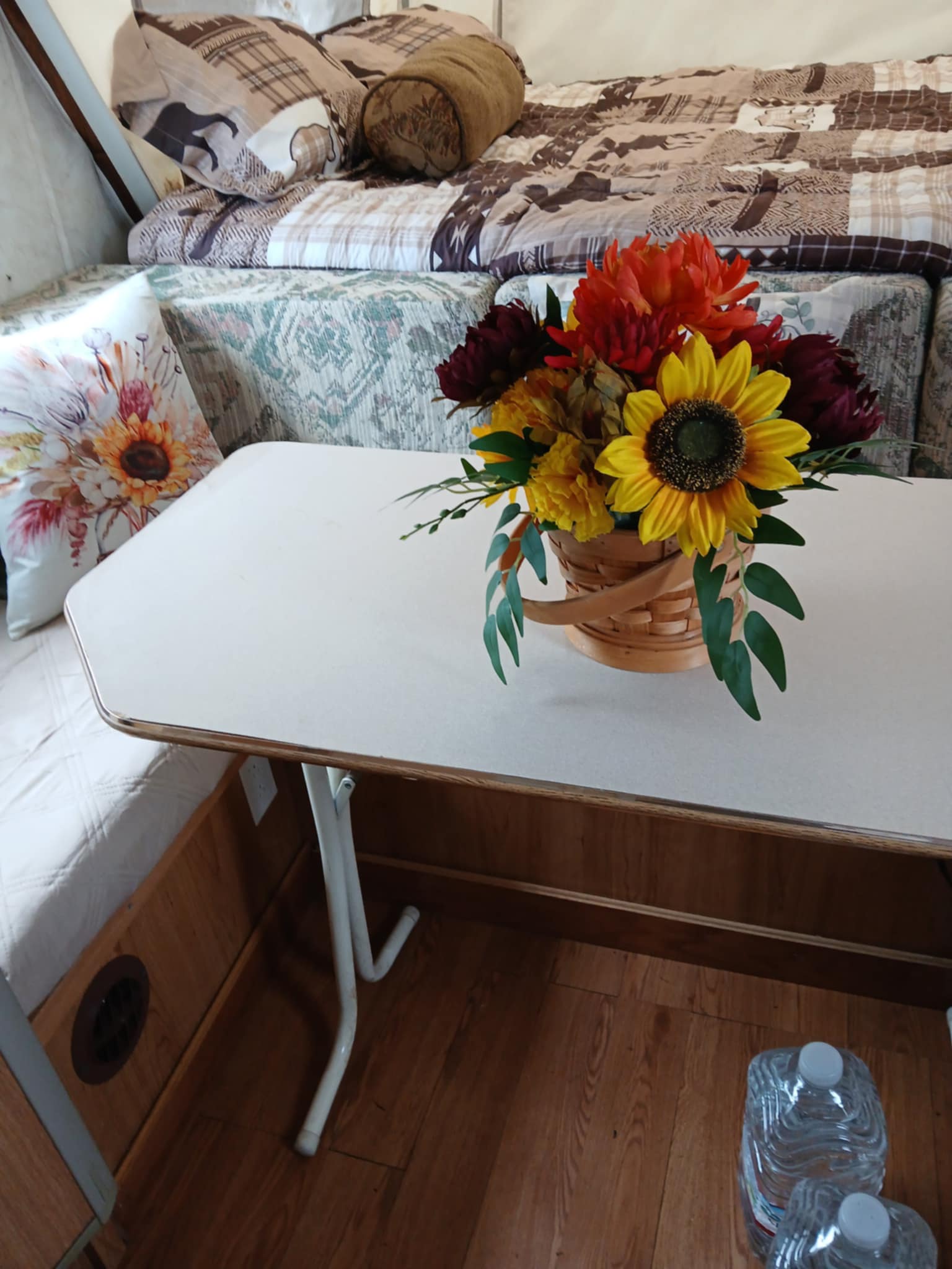 RV rental comfort: A cozy interior with a patterned bed, small table, and vibrant fall flower decor.. Forest River Palomino 2002