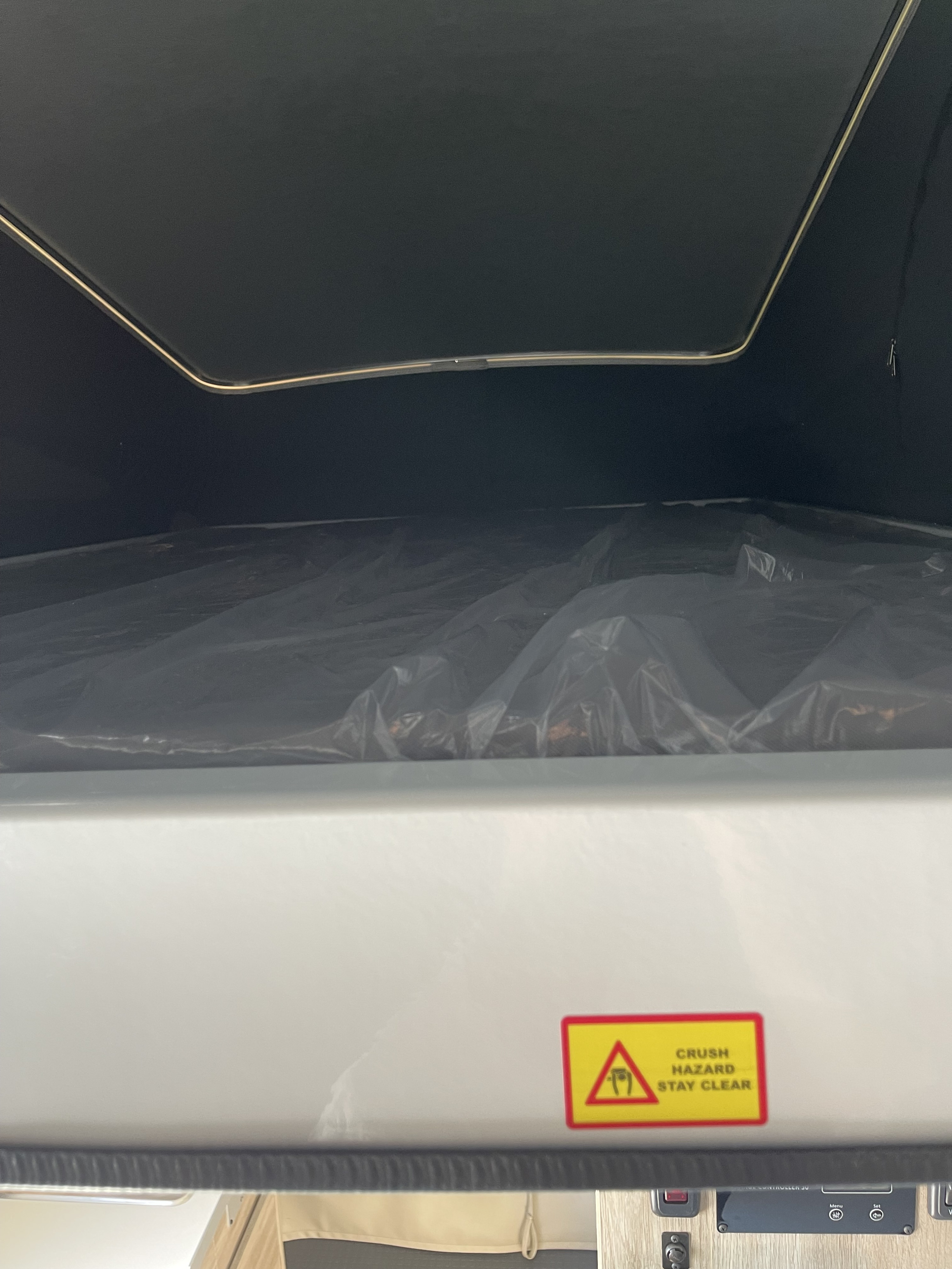 RV rental's upper bunk bed with new, plastic-wrapped mattress and a crush hazard warning label. Safe & ready.. Winnebago Solis 2023