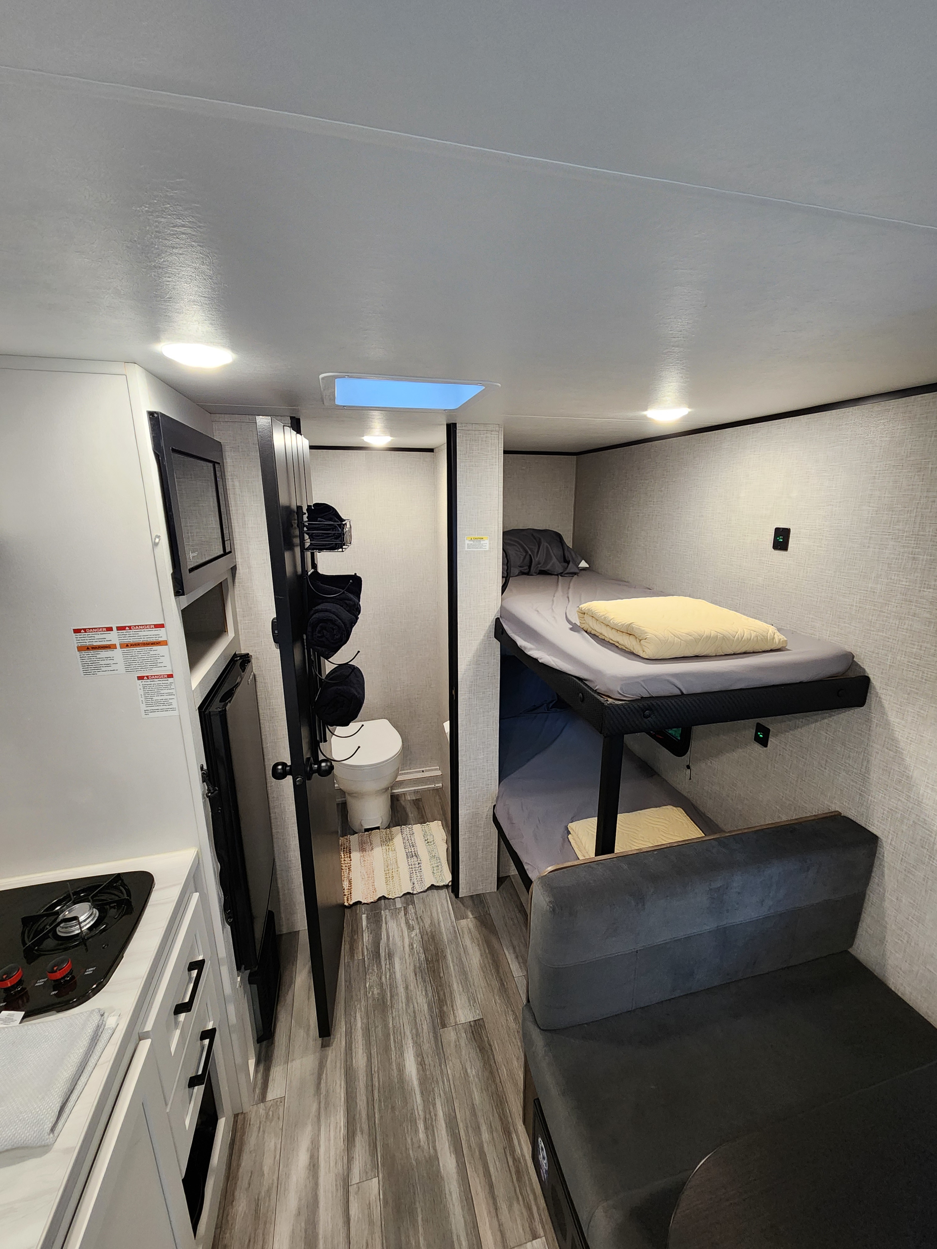 Compact RV rental interior featuring a kitchenette, bathroom, and bunk beds with a dinette, ideal for travel trailer adventures.. Jayco Jay Flight SLX 2024