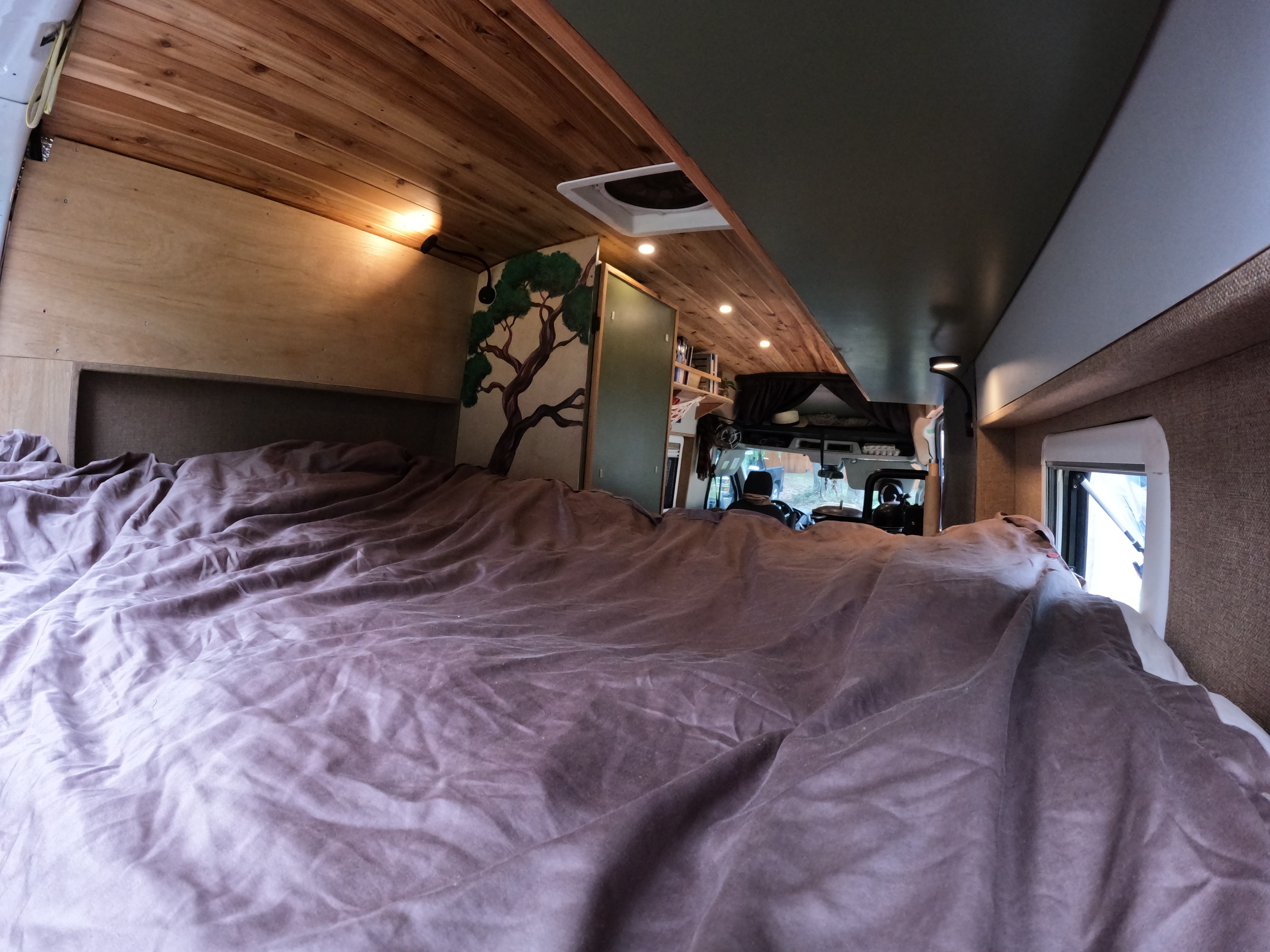 Inside an RV rental: View from the bed towards the front cabin with wood ceilings, custom art, and storage.. Ford Transit 2017