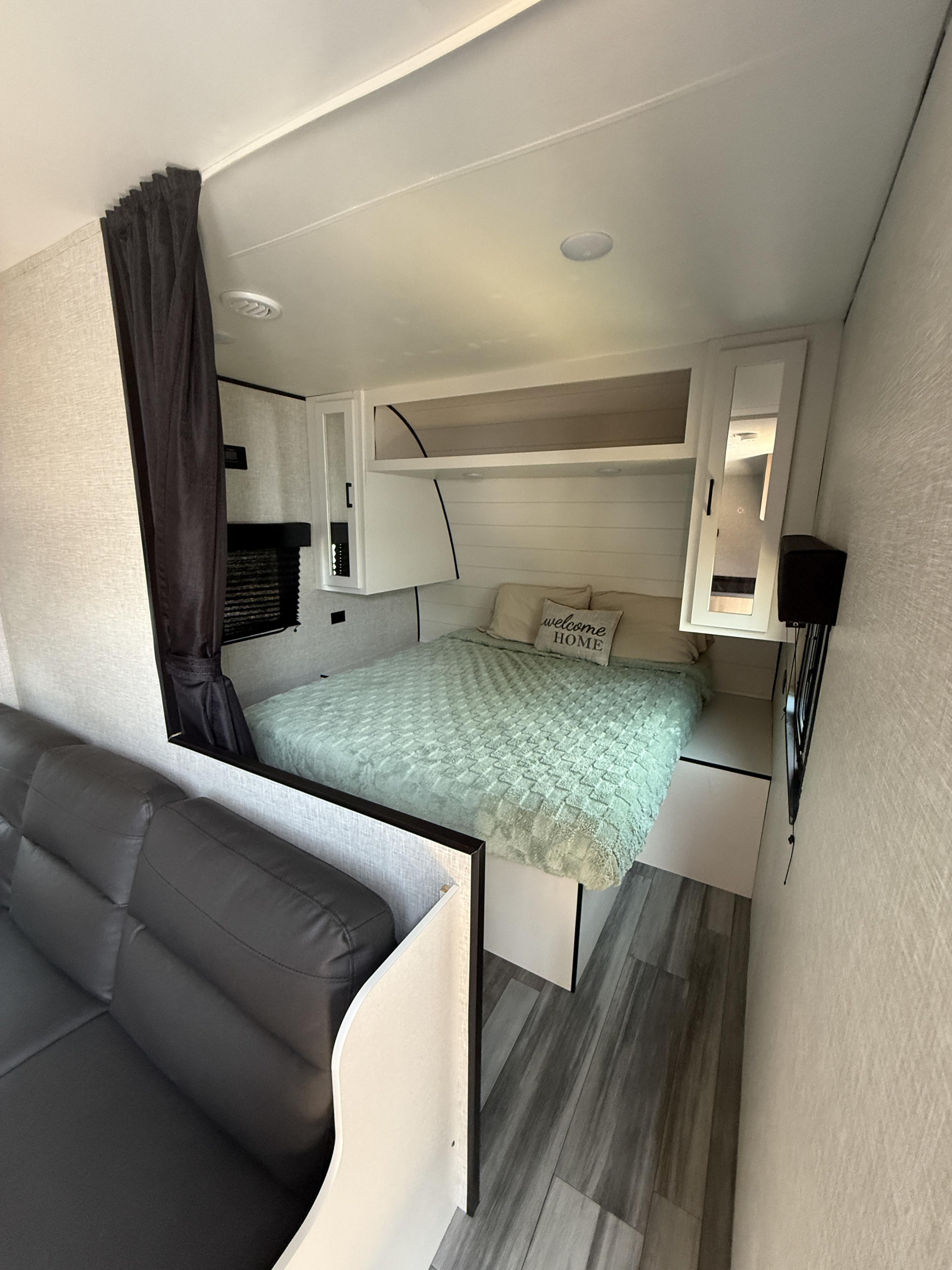 Modern RV rental interior: bedroom with bed & 'welcome HOME' pillow, sofa, TV, and stylish finishes.. Jayco Jay Flight SLX 2024