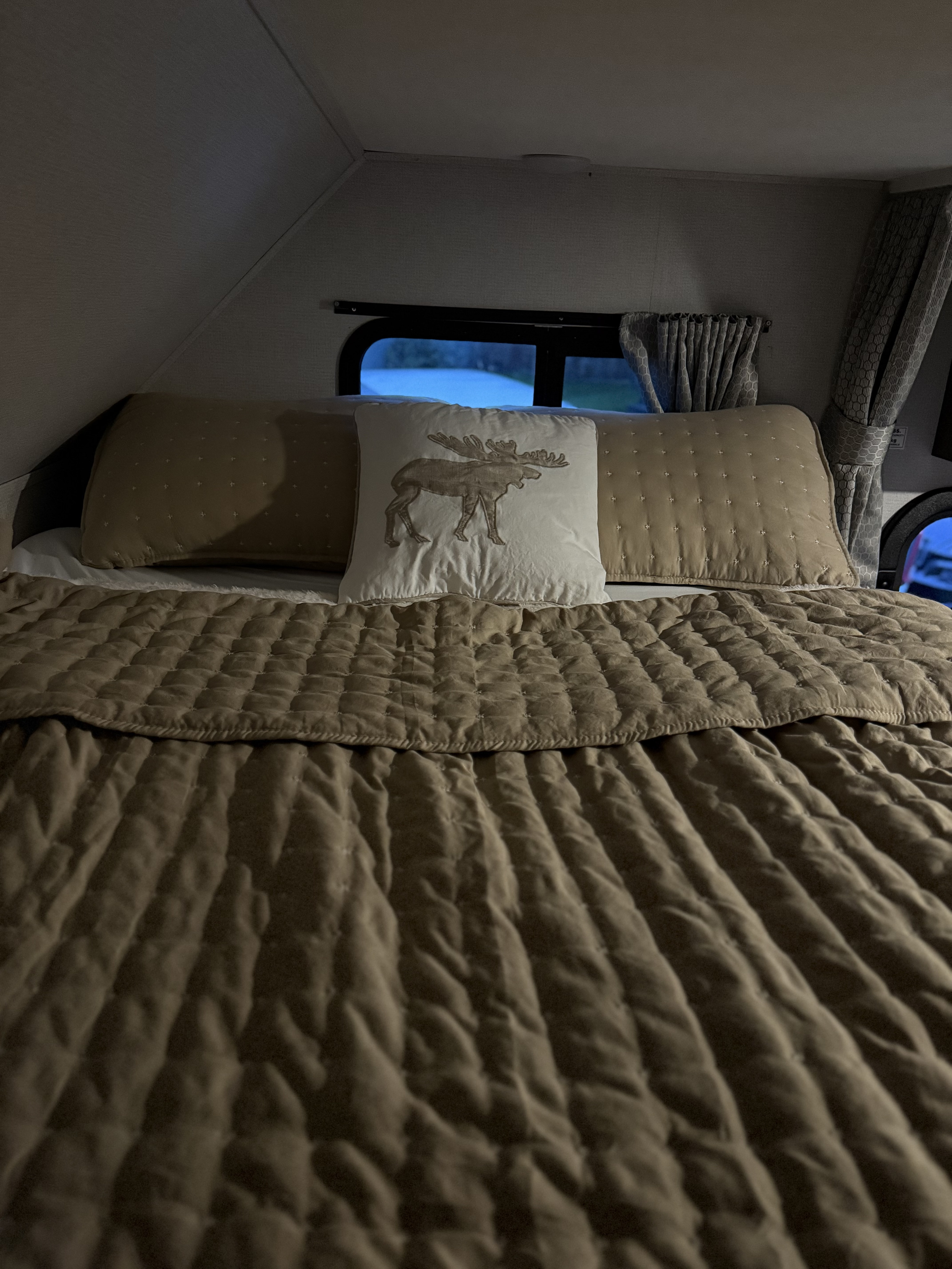 Cozy RV rental bedroom interior featuring a bed with a quilted comforter and a decorative moose pillow.. Forester LE 2022