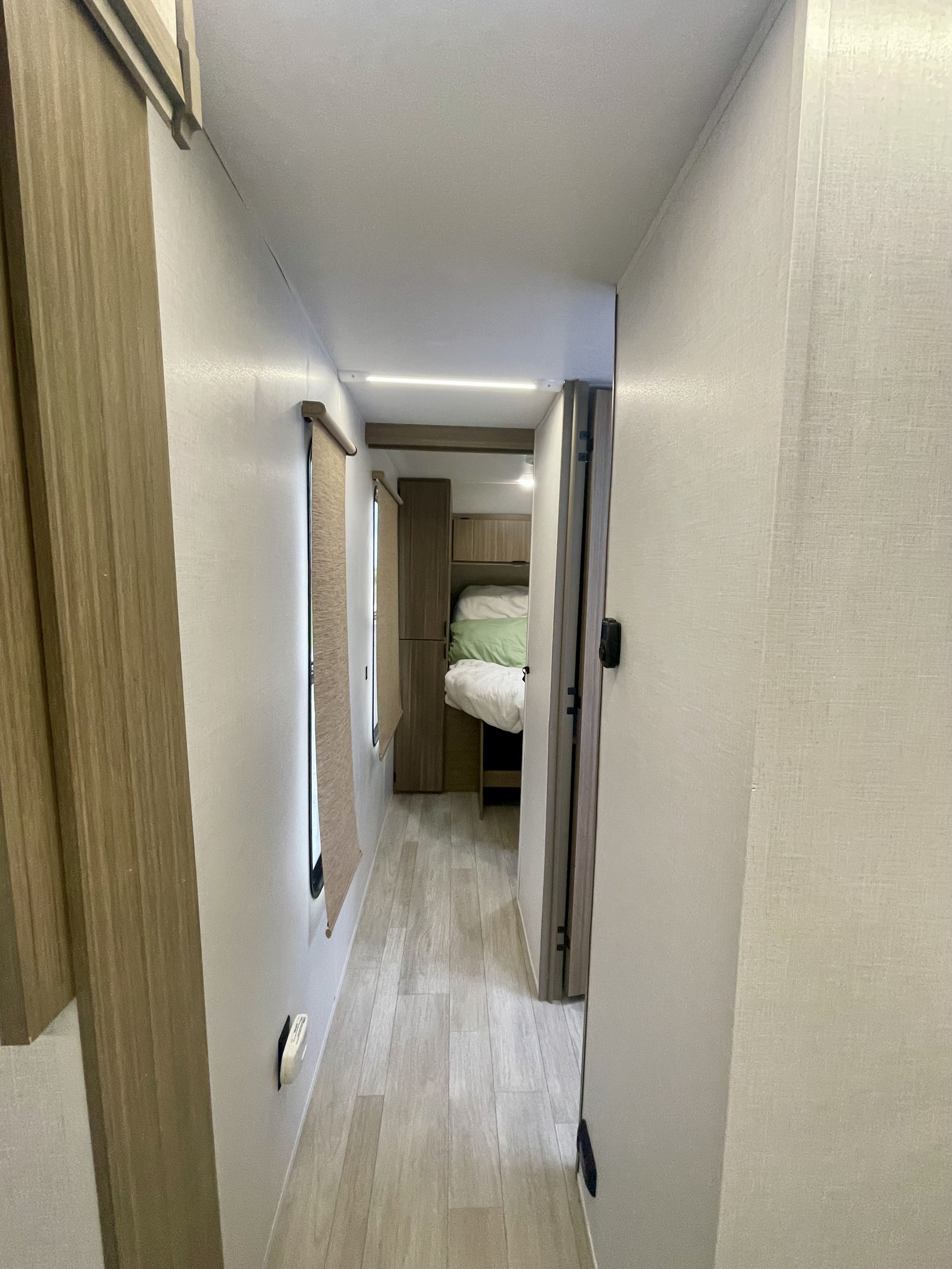 Inside an RV rental: a bright, compact hallway with wood-look floors, leading to a comfortable sleeping area.. Forest River Salem 29BDB 2025