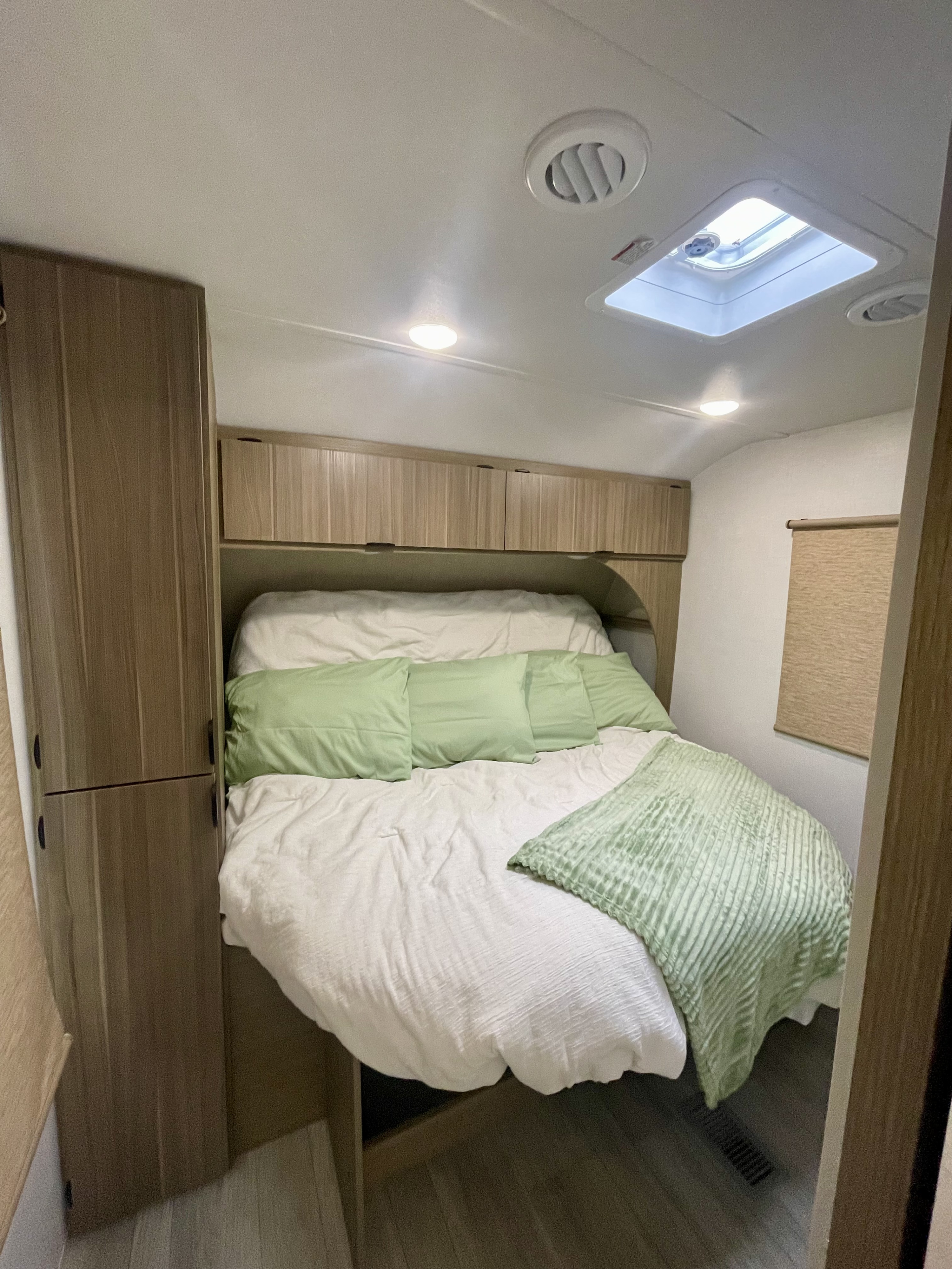 Cozy RV rental bedroom featuring a comfy bed with green accents, overhead storage, skylight, and closet.. Forest River Salem 29BDB 2025