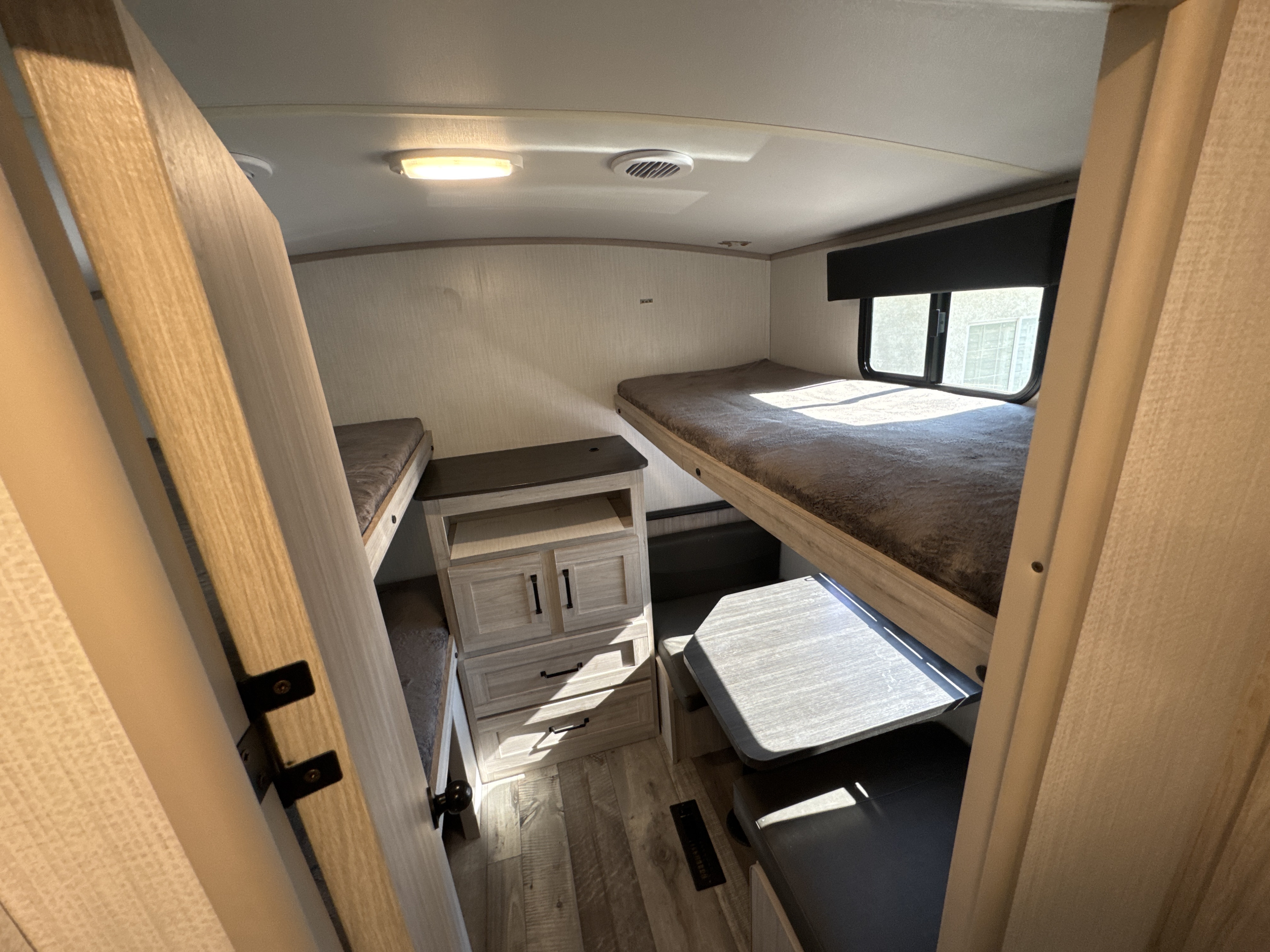 Spacious RV rental interior showing a bunkhouse with two bunk beds, a dinette, and storage cabinet.. Heartland RVs Sundance Ultra Lite 2024