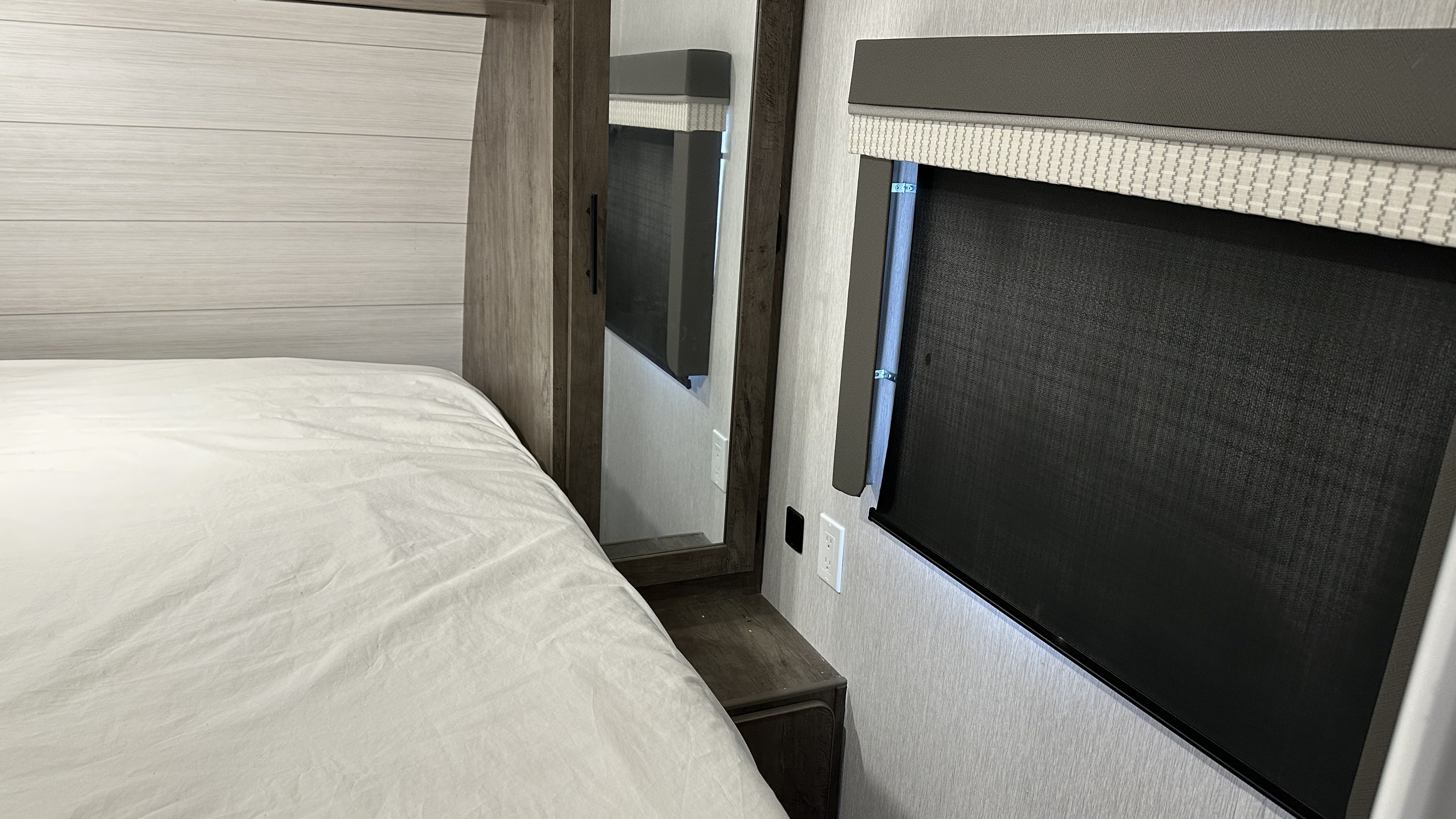 Inside an RV rental: a compact bedroom featuring a white bed, wood paneling, and a dark window blind.. Forest River Salem Cruise Lite 2022