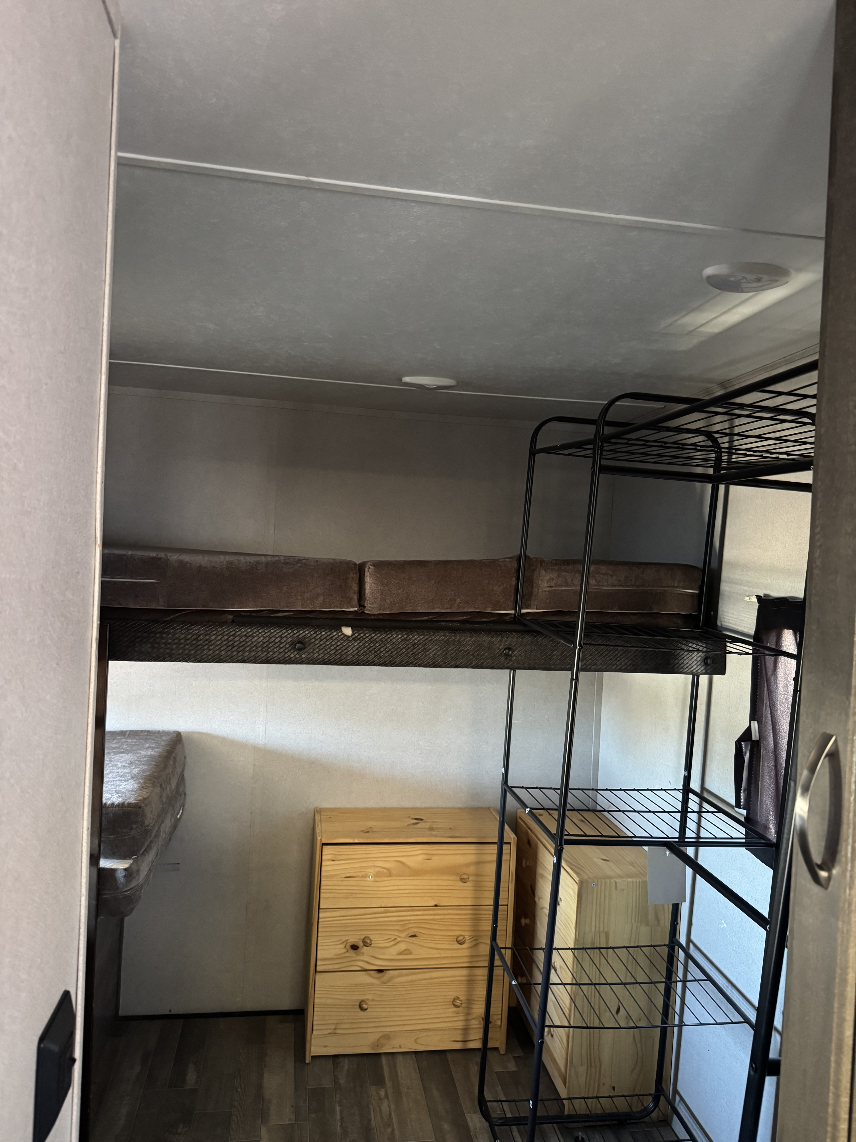 RV rental: Compact bunk bed area with a metal ladder, brown mattresses, and natural wood storage drawers inside.. Forest River vibe 2020