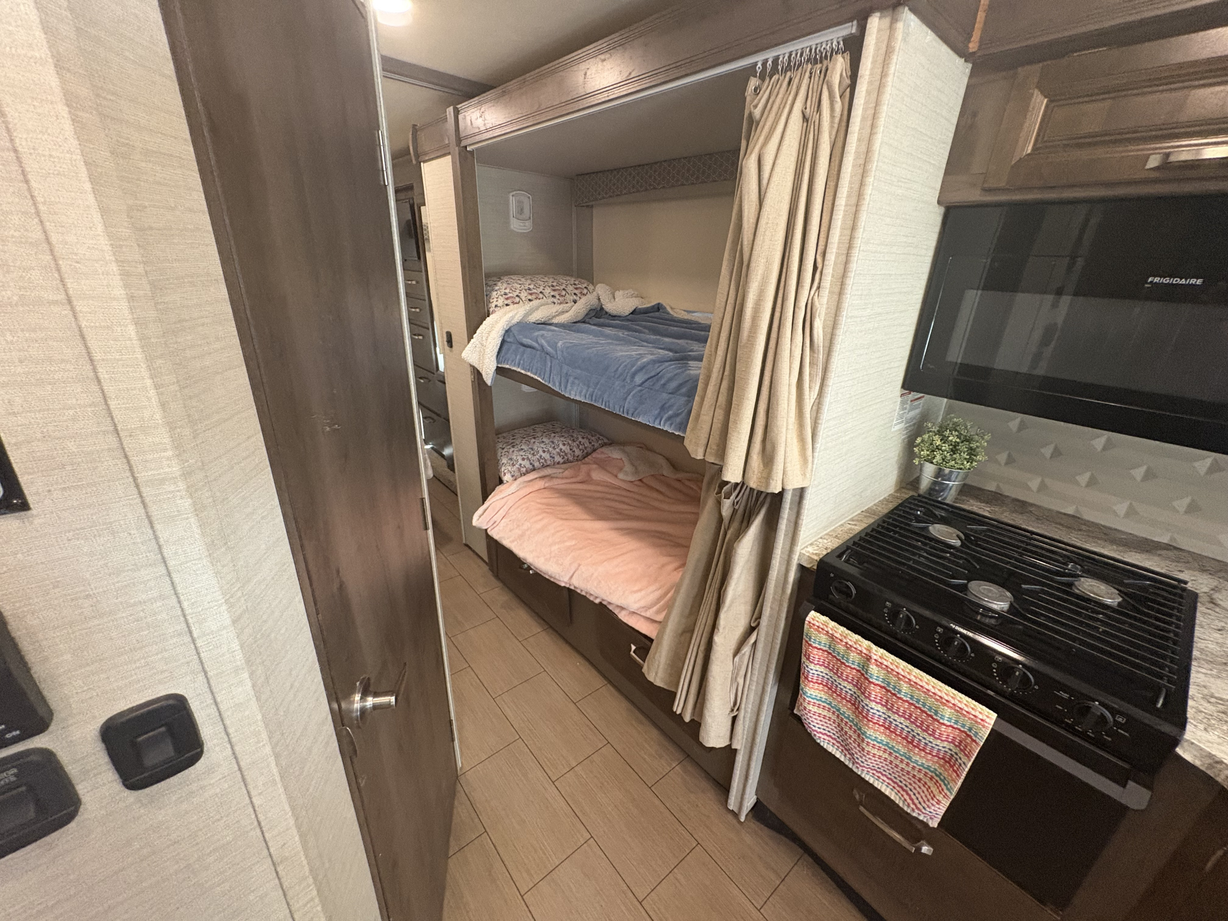 This RV rental features cozy bunk beds with privacy curtains, a compact kitchen with a stove and microwave, and wood-look flooring.. Jayco Greyhawk 2019