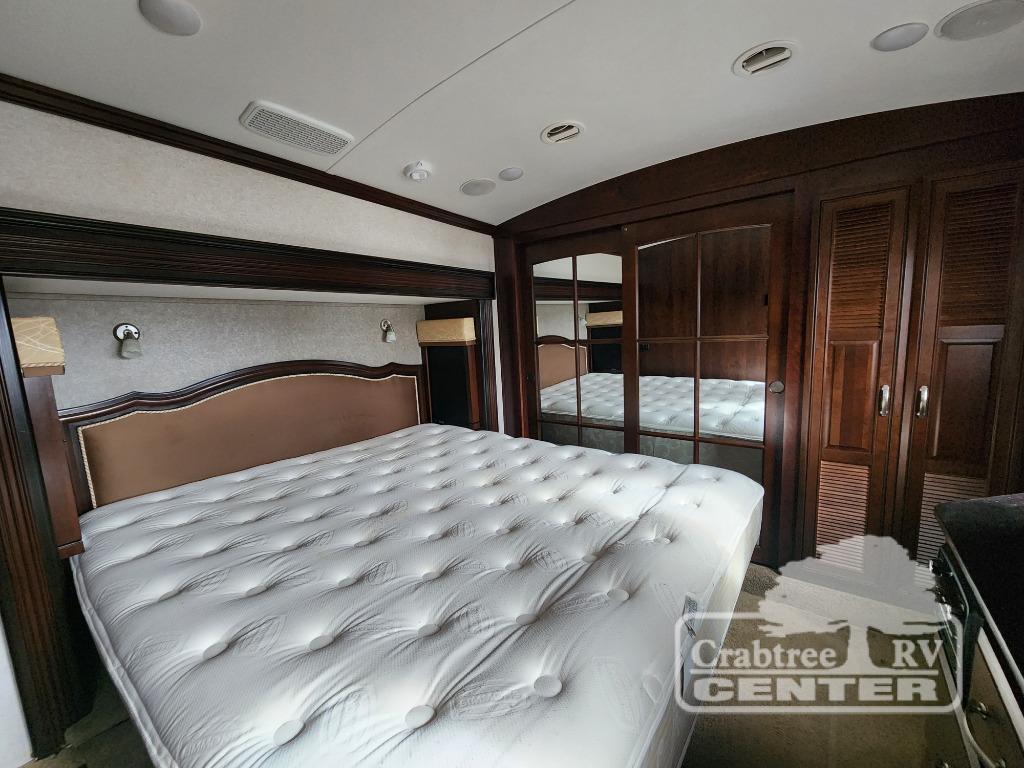 RV rental bedroom: a plush tufted mattress, elegant upholstered headboard, and mirrored closets set in rich wood cabinetry.. Jayco Designer 39RE 2017