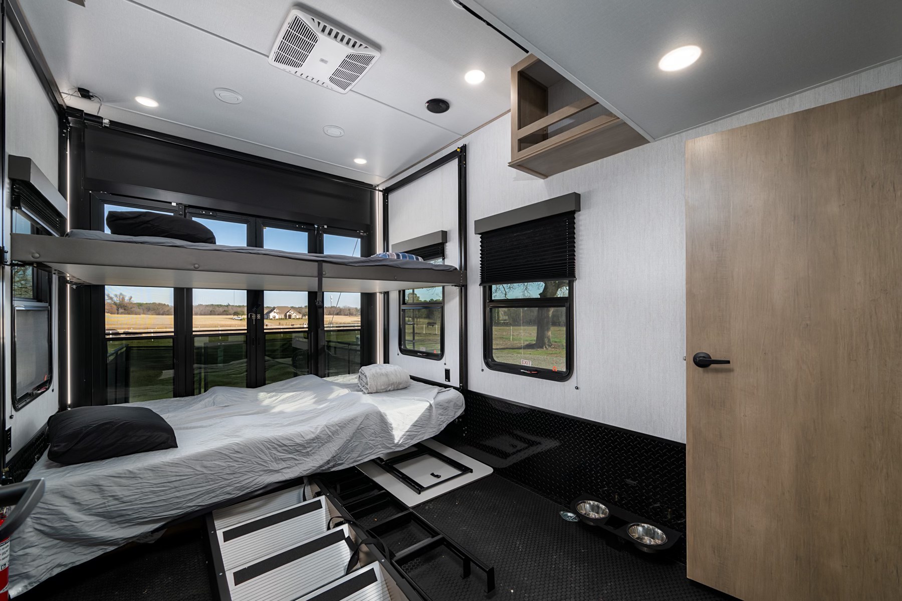 Inside a modern rv rental toy hauler: comfy bunk beds, large windows, and a versatile cargo area with pet bowls.. Grand Design Momentum 2024