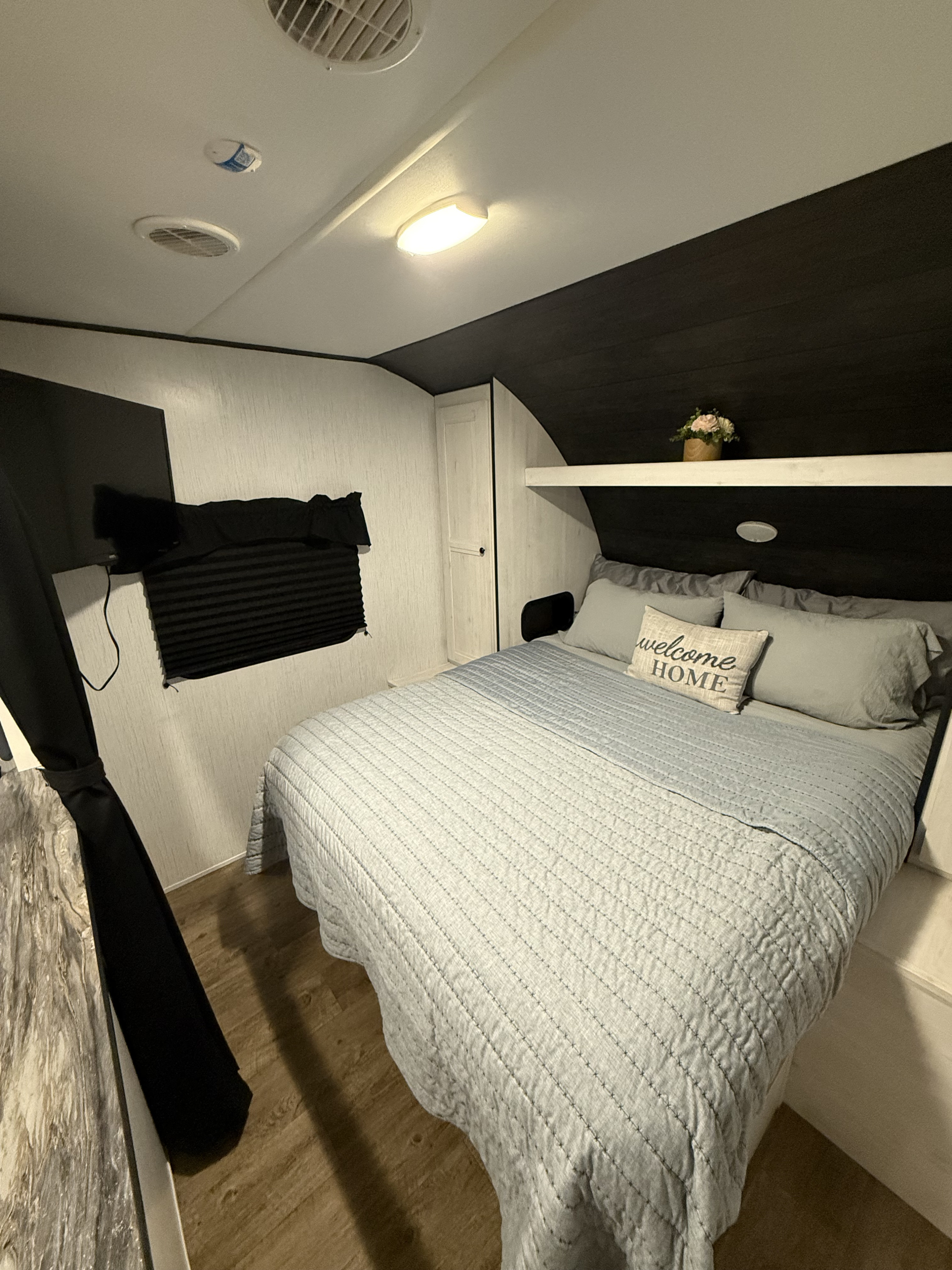 RV rental: Relax in this cozy bedroom with light blue bedding, a 'welcome HOME' pillow, TV, and ample storage.. Heartland RVs Trail Runner 2022