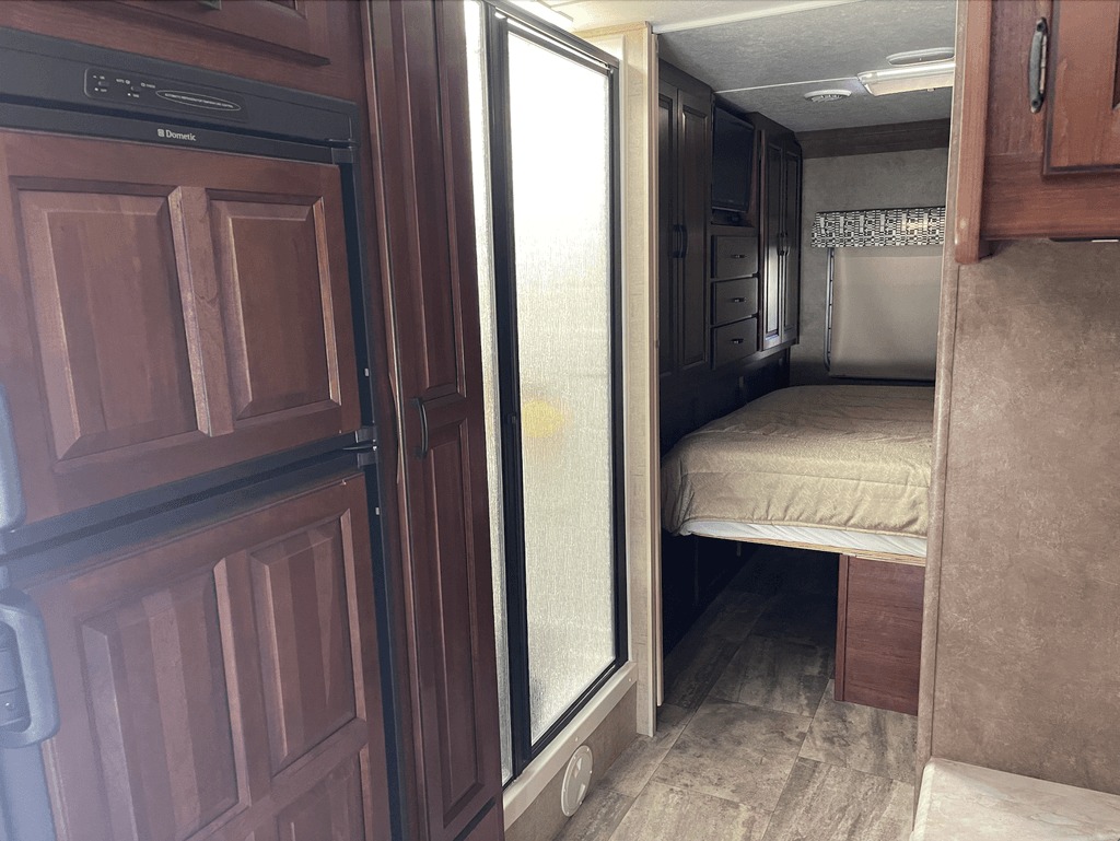 RV rental interior: Dometic fridge, glass shower, and bedroom with wood cabinets & TV for compact living.. Forest River Sunseeker 2016
