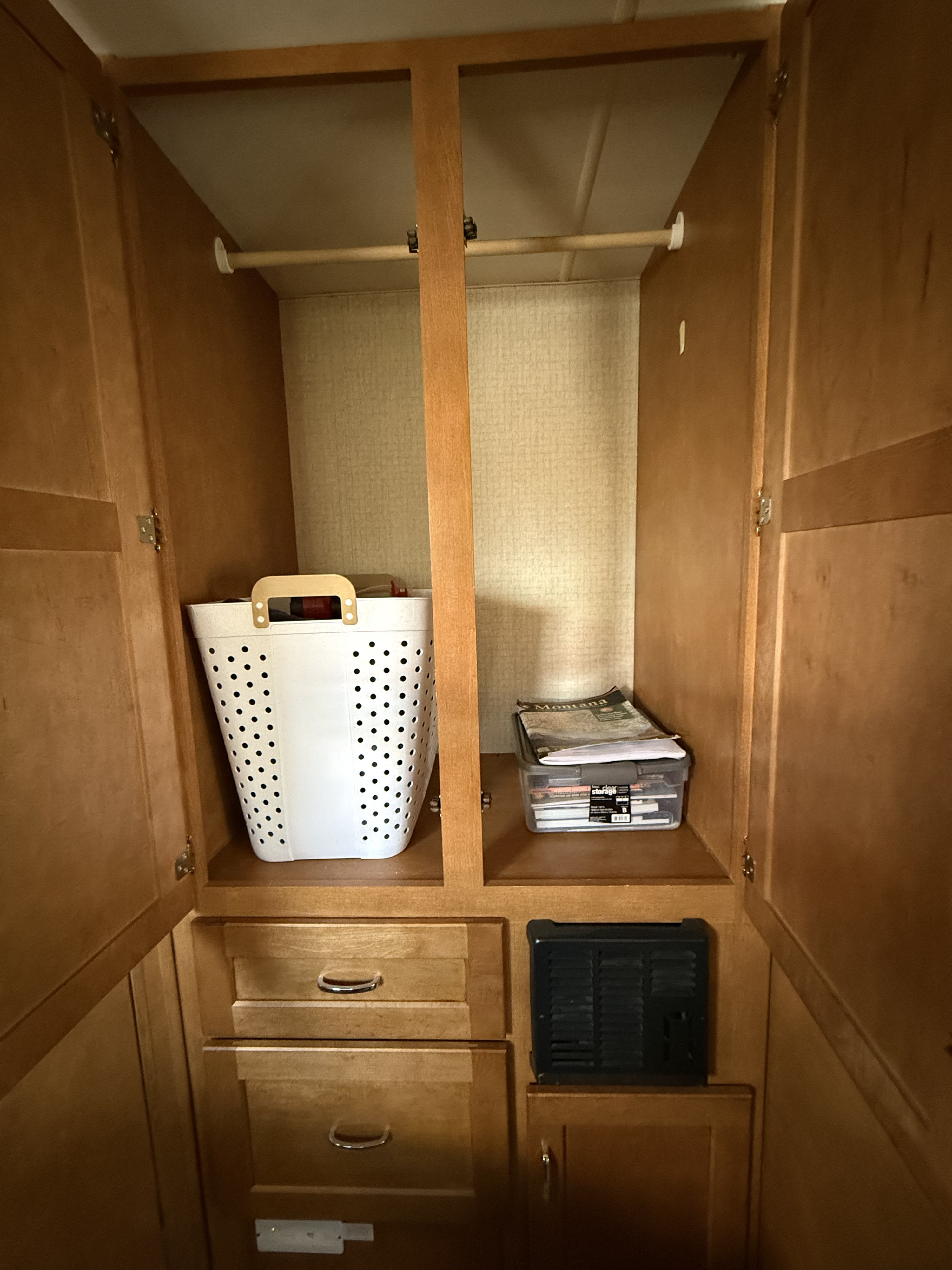 Inside an RV rental: a wood closet/cabinet with hanging rod, laundry hamper, clear storage bin, and drawers below.. Winnebago Minnie Winnie 2016