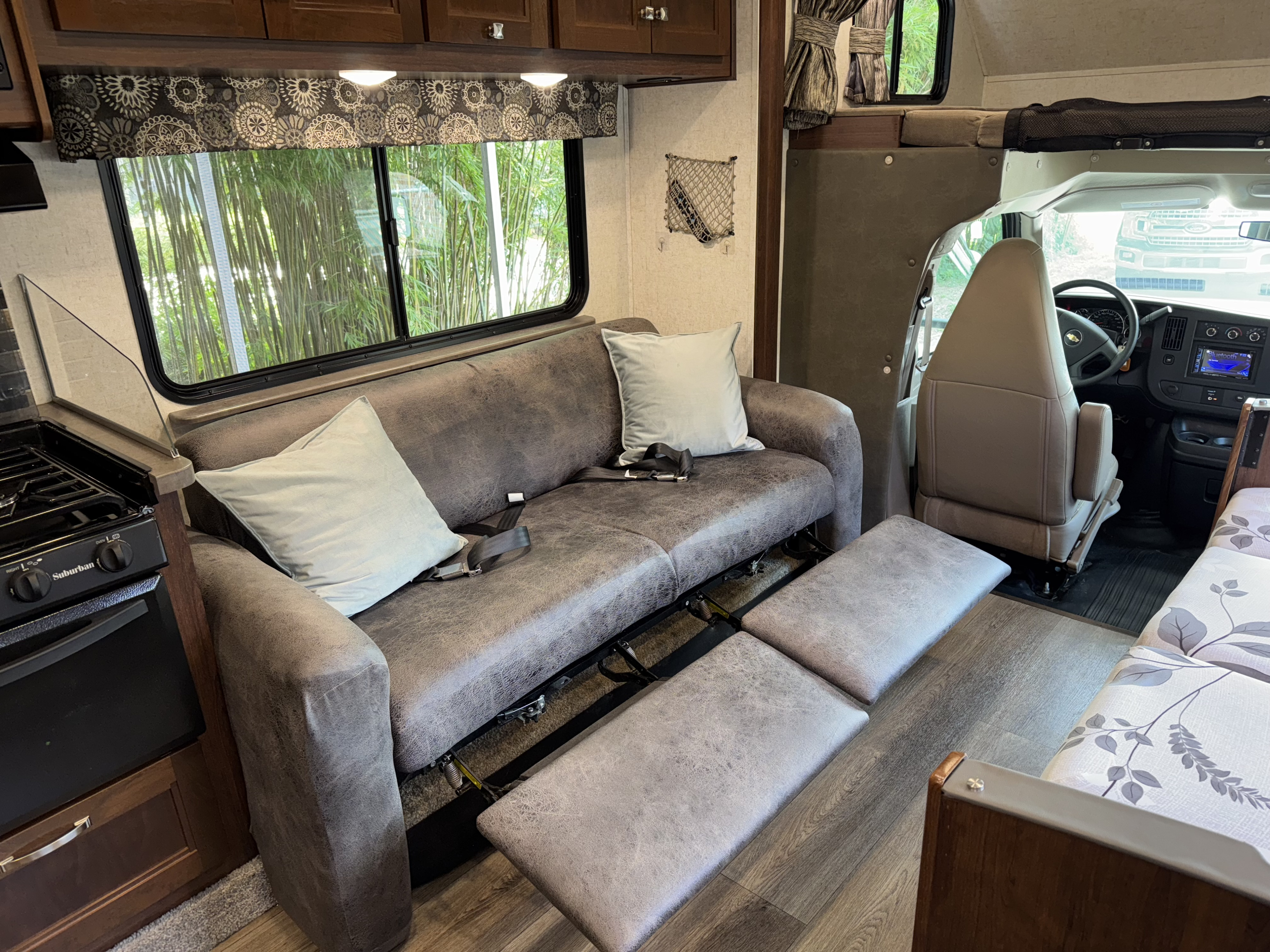 Spacious RV rental interior featuring a cozy bed, seating area, and overhead storage. Ideal for comfortable travel.. Forest River Sunseeker 2017