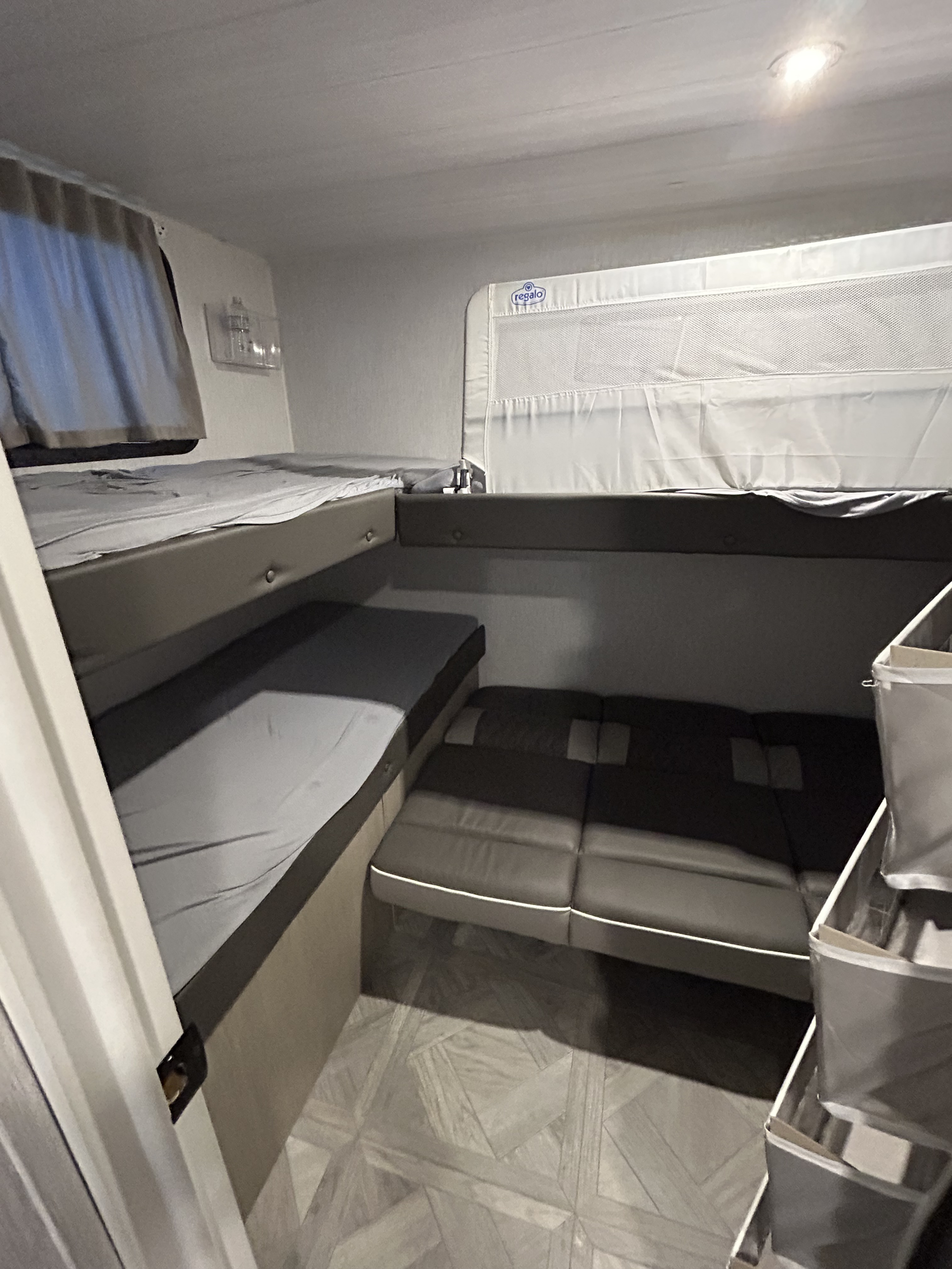 Cozy RV rental interior featuring a bunk bed with a baby safety rail, bench seating, and patterned floor.. Forest River Wildwood X-Lite Platinum 2023