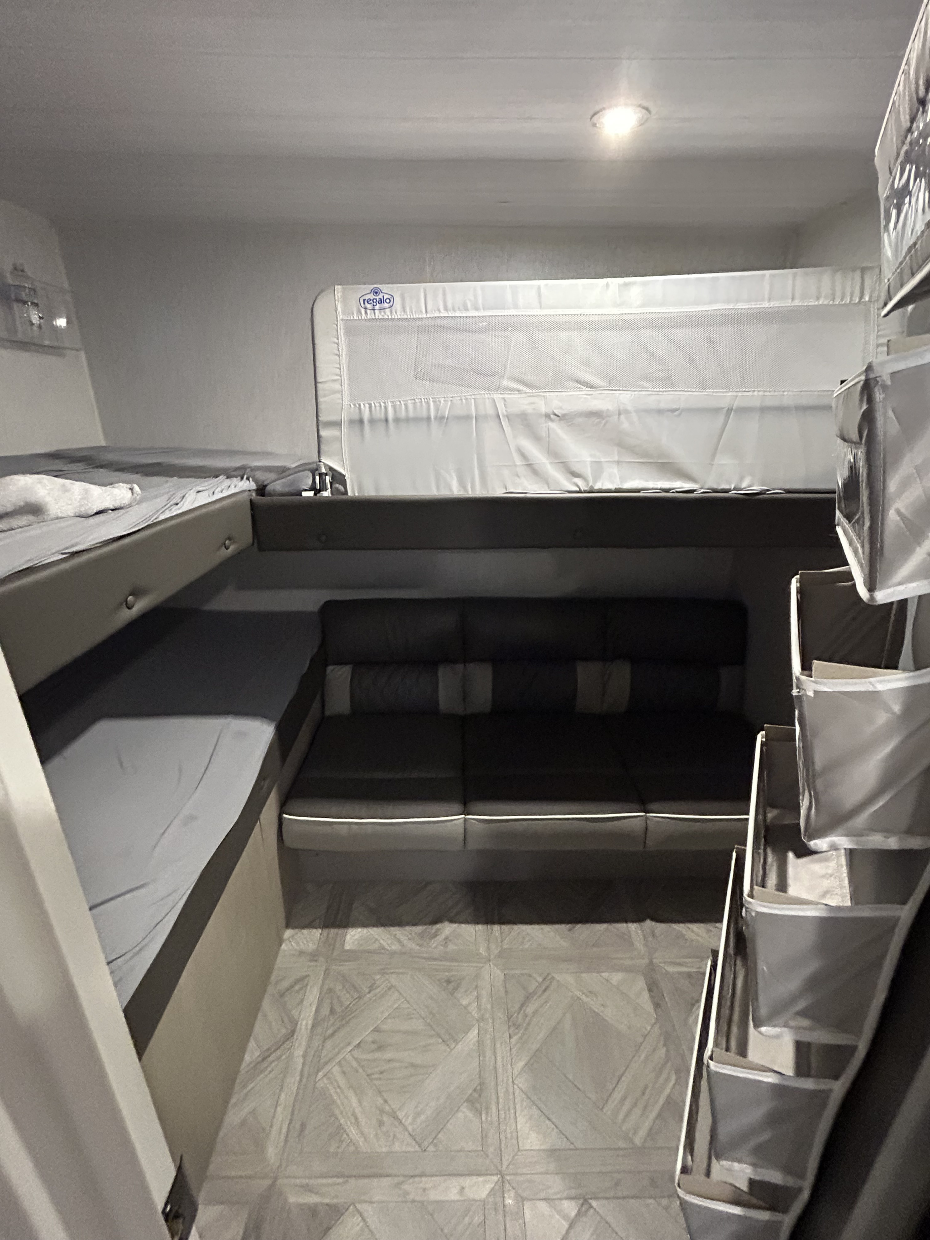 Cozy RV rental interior: bunk bed with safety rail, convertible sofa, and hanging storage for a family trip.. Forest River Wildwood X-Lite Platinum 2023