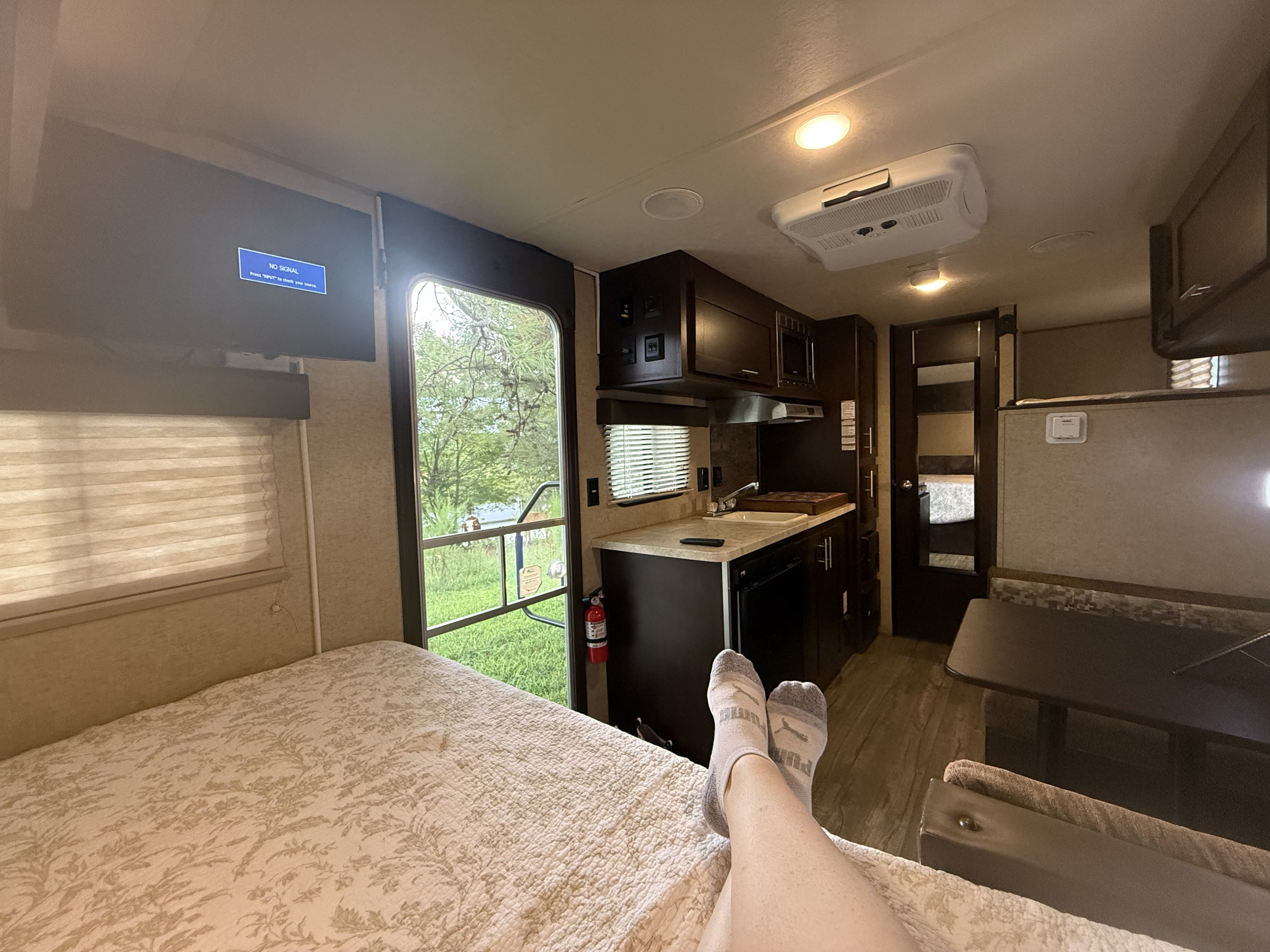 Relaxing RV rental interior featuring a cozy bed, full kitchen, and scenic outdoor view. Ideal for travel and vacations.. Forest River Cherokee Wolf Pup Cascade 2017