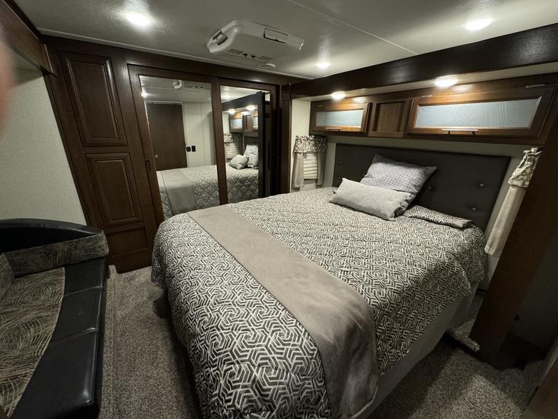 Spacious RV rental bedroom featuring a comfy bed, mirrored closet, and overhead storage, ideal for your next trip.. Forest River Wildcat 2019