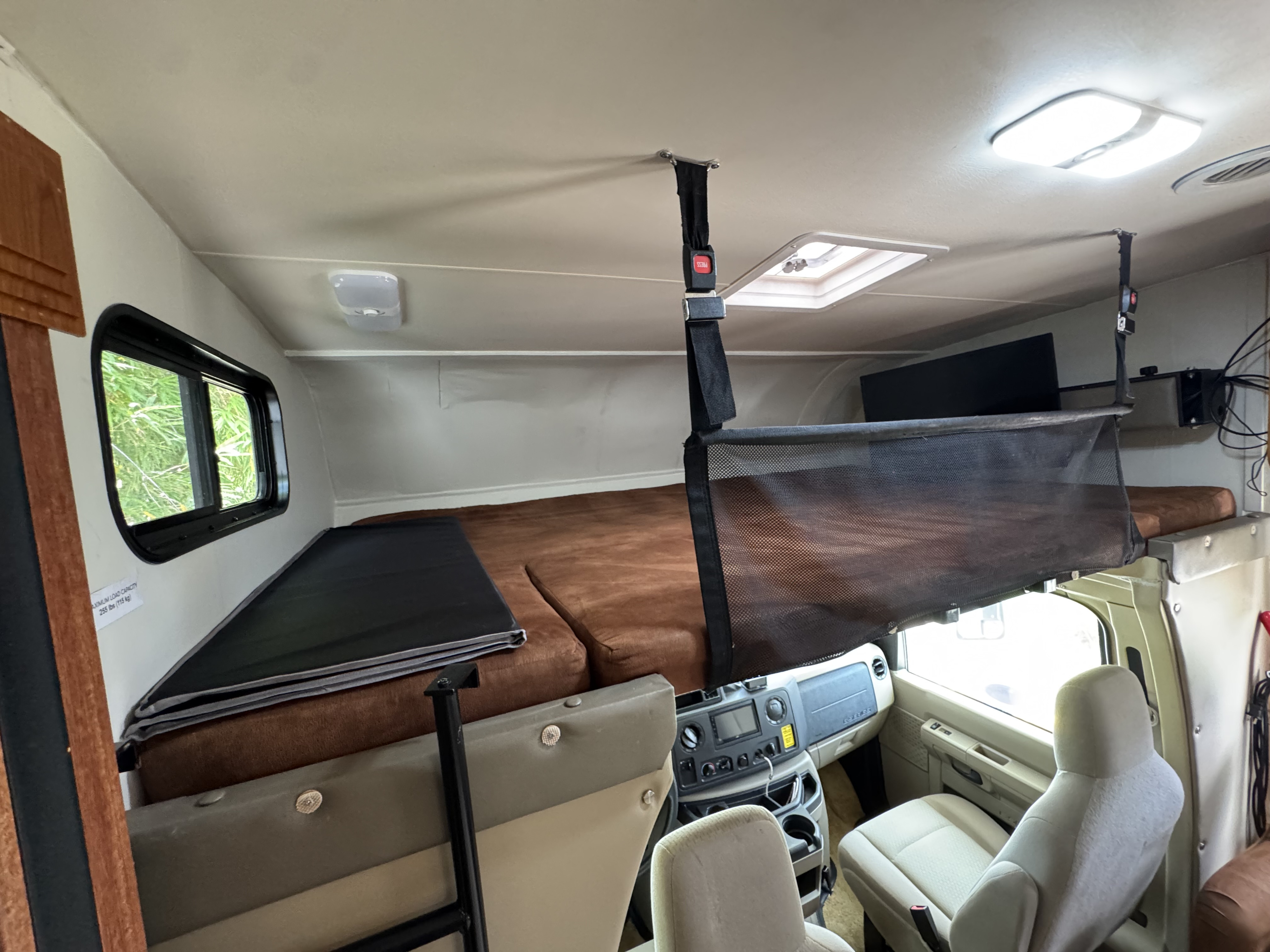 Interior of an **RV rental** featuring a cozy overhead bunk bed with safety net and view of the driver's cabin.. Forest River Coachmen Freelander 2011