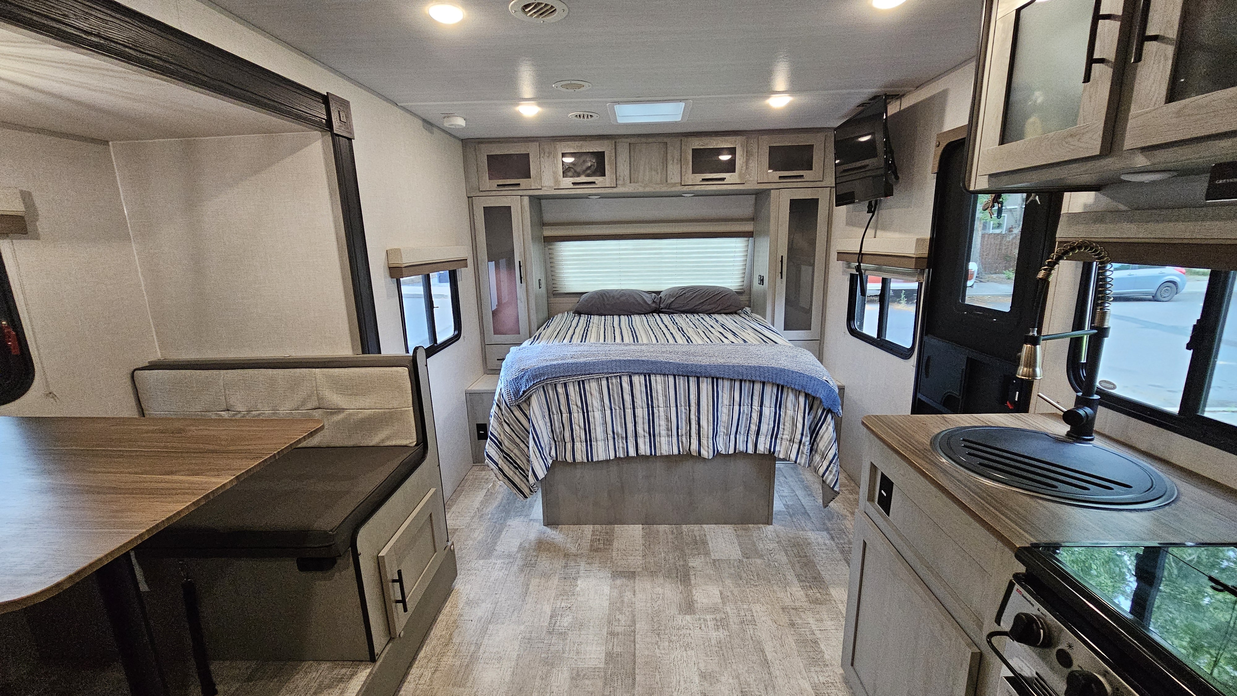 Spacious RV rental interior with bedroom, dining booth, & compact kitchen, ideal for travel. Modern, clean design.. Forest River Ibex 2024