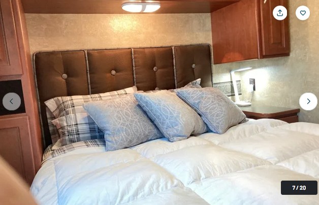 Cozy RV rental bedroom featuring a tufted headboard, plush bedding, and built-in storage. Ideal for comfortable travel.. Winnebago Minnie Winnie 2015