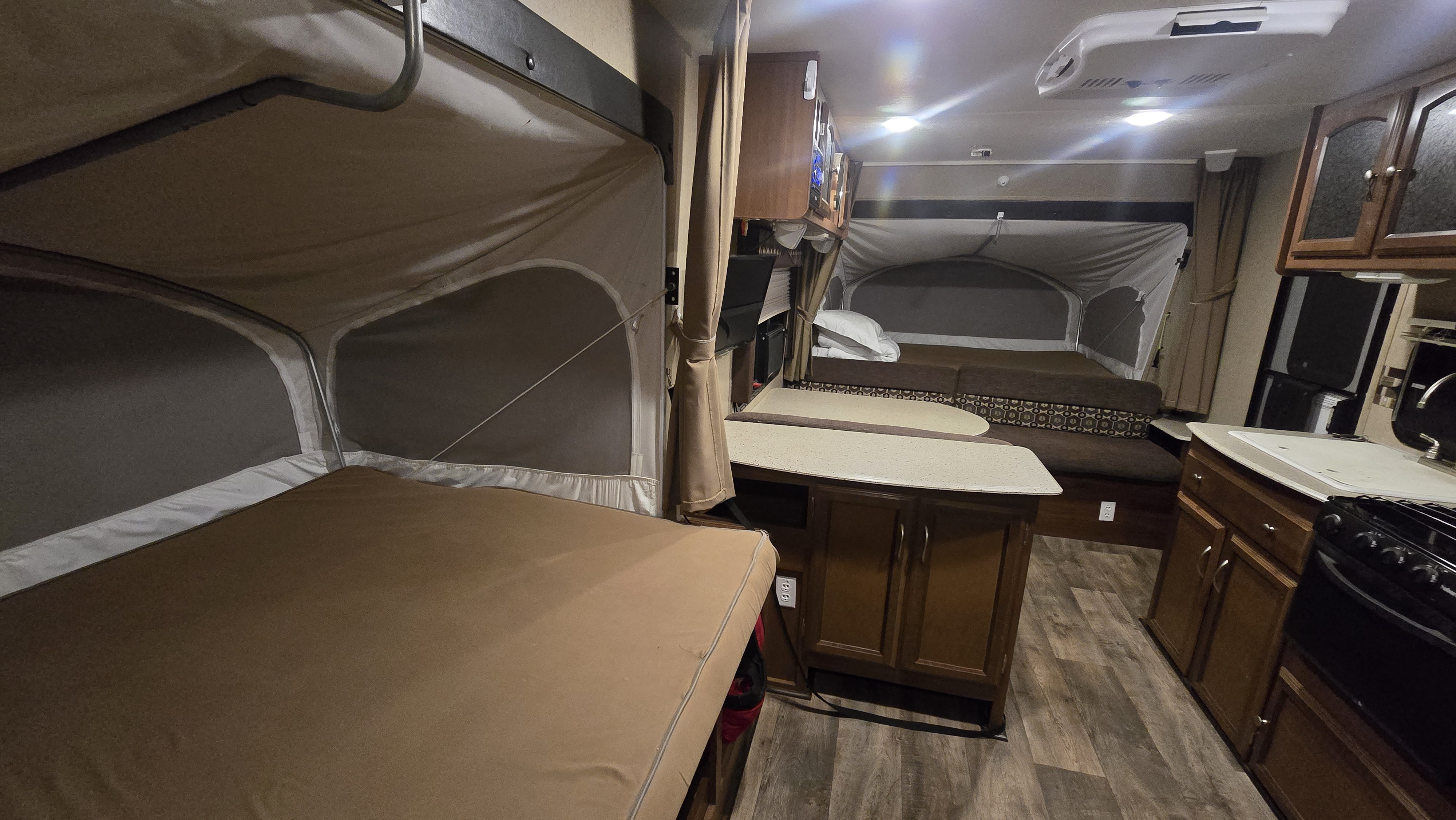 Cozy rv rental interior featuring two pop-out beds, a dining area, and full kitchen, perfect for a comfortable road trip.. Coachmen Freedom Express 2015