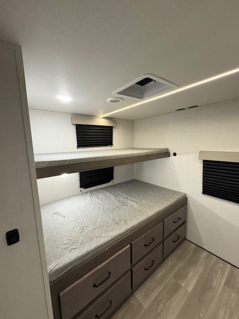 Bright RV rental bunk room with dual beds and storage drawers. Perfect sleeping area for family travel in this modern trailer.. Grand Design Transcend Xplor 2024