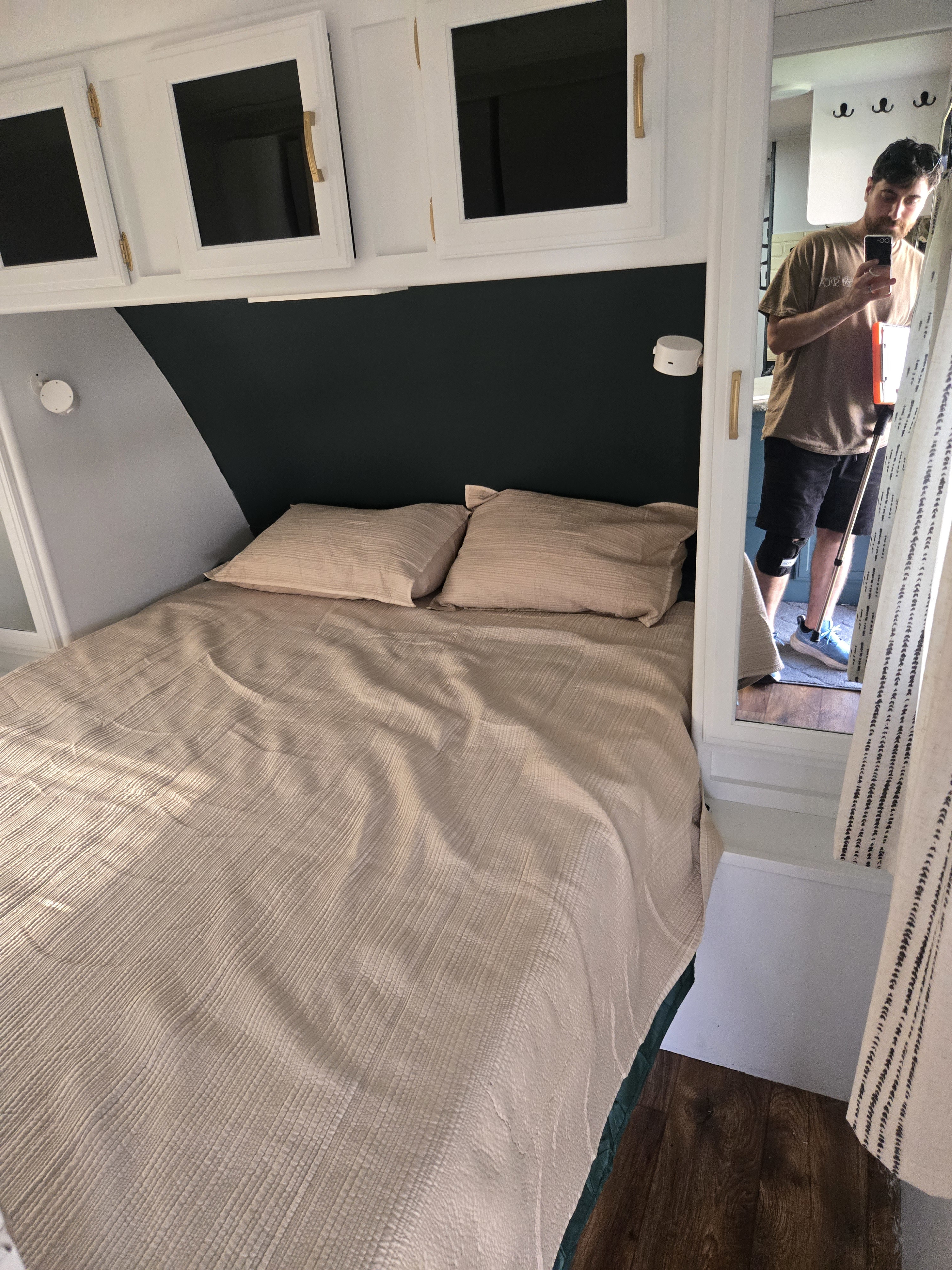 Cozy RV rental bedroom with light bedding, sleek white cabinets, and a mirror showing the modern interior design.. Keystone RV Passport Grand Touring 2015