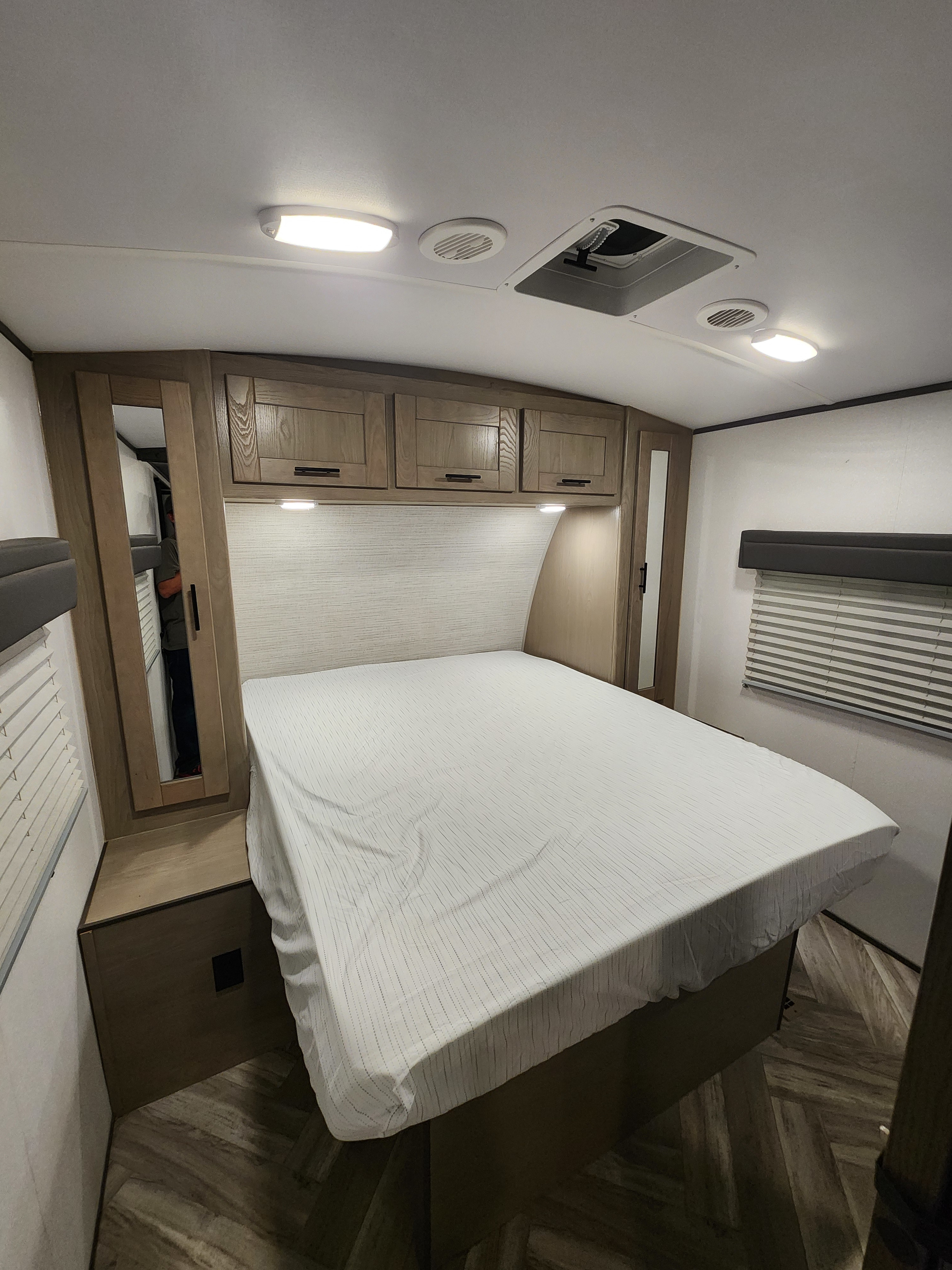 A comfortable RV rental bedroom features a queen bed with overhead storage, a mirrored closet, and window blinds.. Cruiser RV Shadow Cruiser 2021
