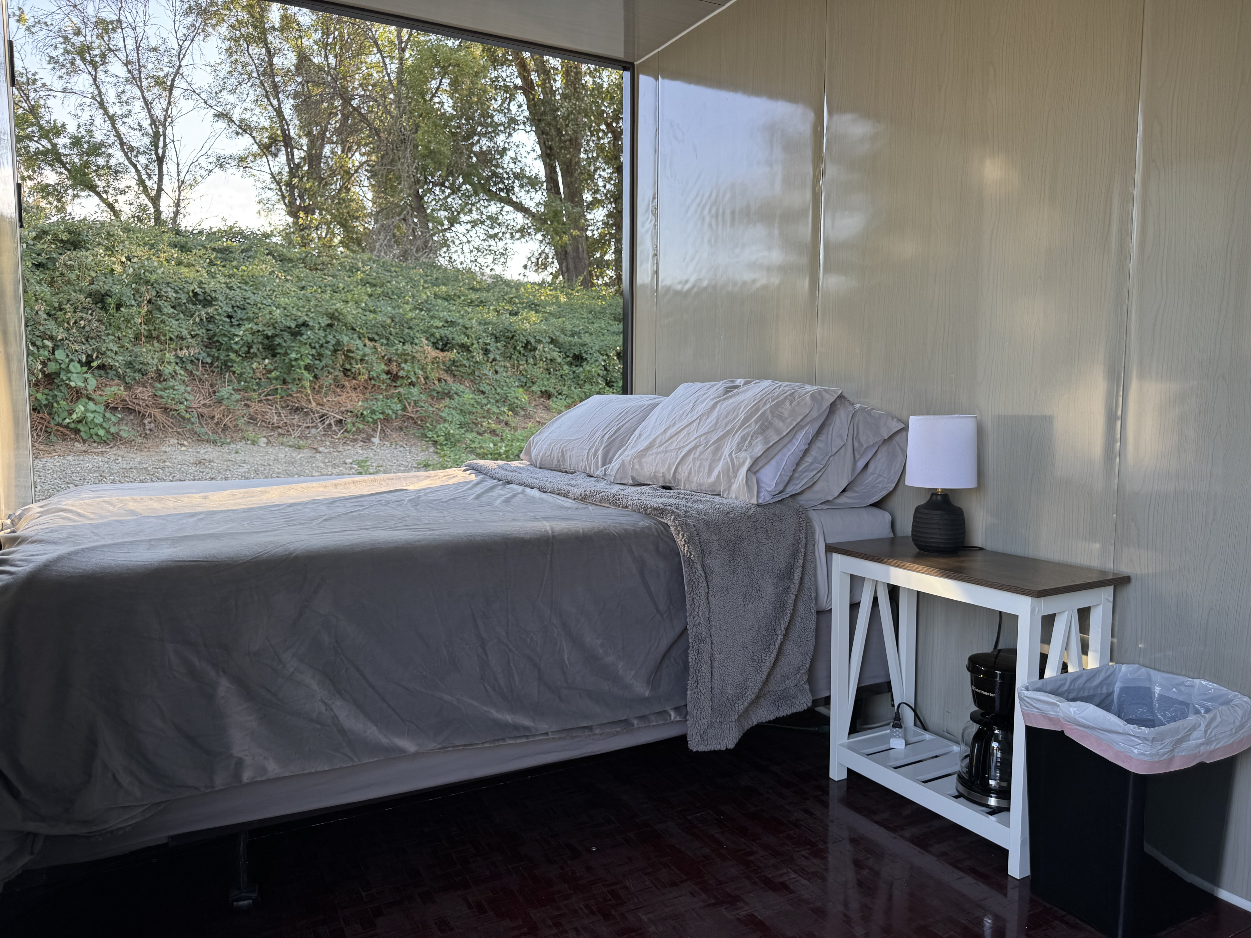 Cozy RV rental bedroom with a comfy bed, nature view window, and coffee maker, perfect for a glamping escape.. Ford F350 2025