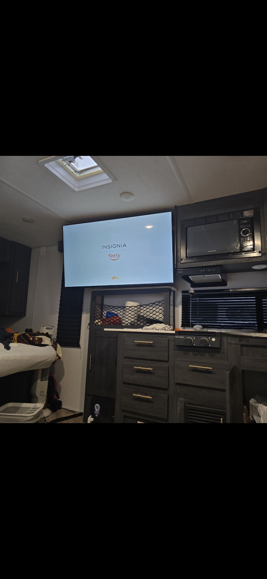 RV rental interior showing an Insignia Fire TV, built-in microwave, storage units, and a cozy sleeping area.. Ozark Ascent 2022