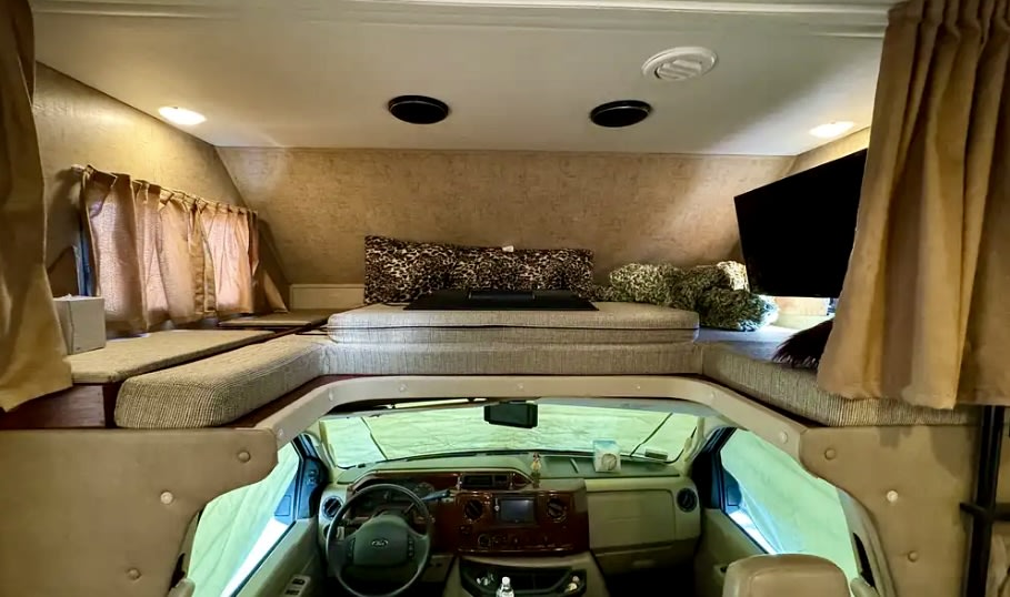 Spacious overhead bunk with a bed & TV in an RV rental. View of the driver's cab below for a full interior perspective.. Forest River Forester 3171DS 2016