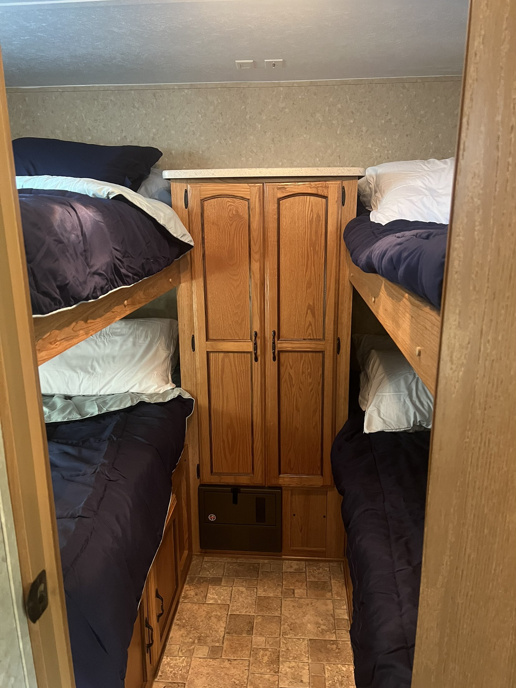 Cozy bunk beds in an RV rental sleeping area with a central cabinet, perfect for camper adventures.. Forest River Palomino Puma 2010