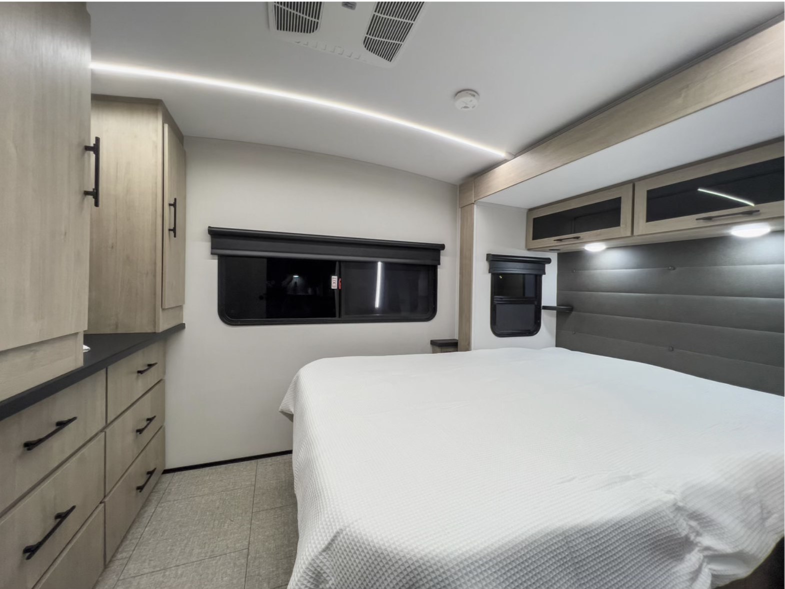 Spacious RV rental bedroom featuring a comfortable bed, modern cabinetry, ample storage, and ambient lighting.. Grand Design Imagine 2024