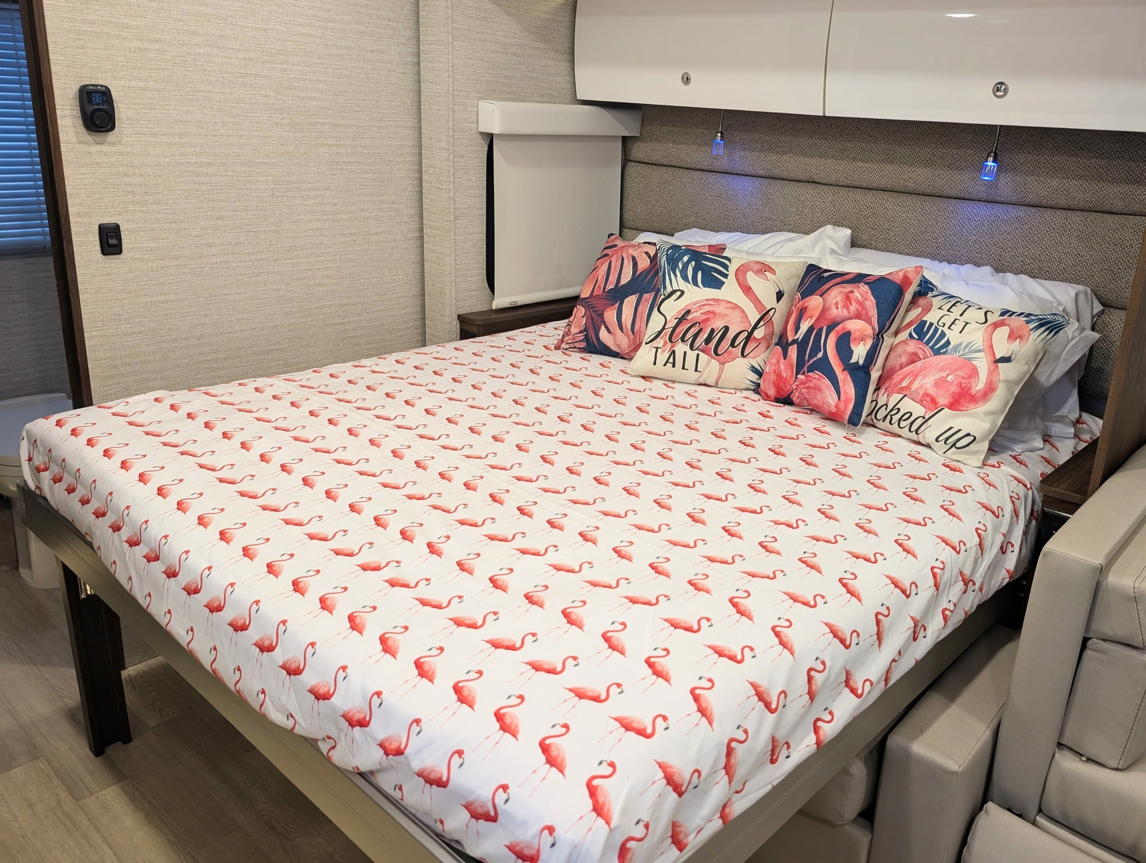 Bright flamingo bed in an RV rental, featuring custom bedding & throw pillows, creating a fun and cozy interior.. Winnebago View 2025