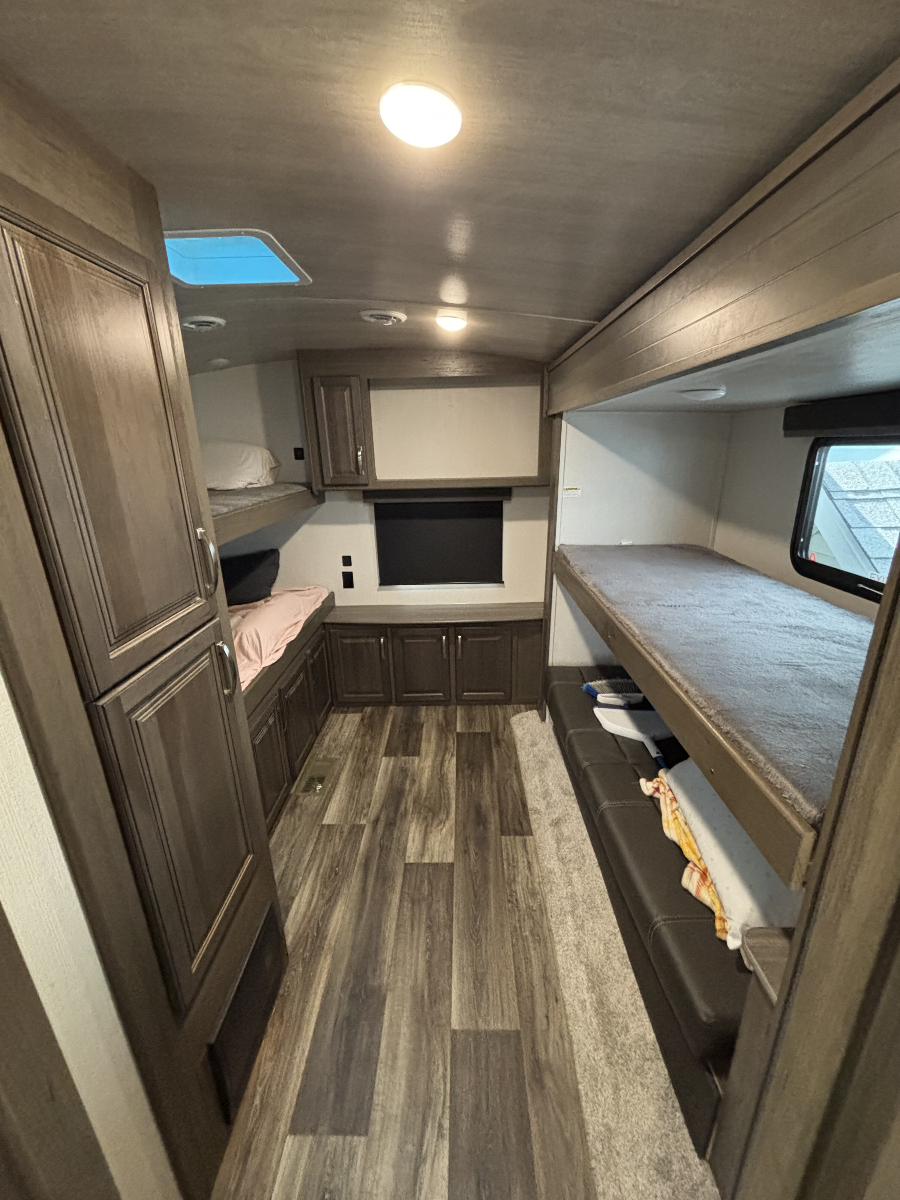 Clean RV rental bunkhouse interior featuring multiple sleeping bunks and modern wood-look flooring.. Keystone RV Cougar 2023