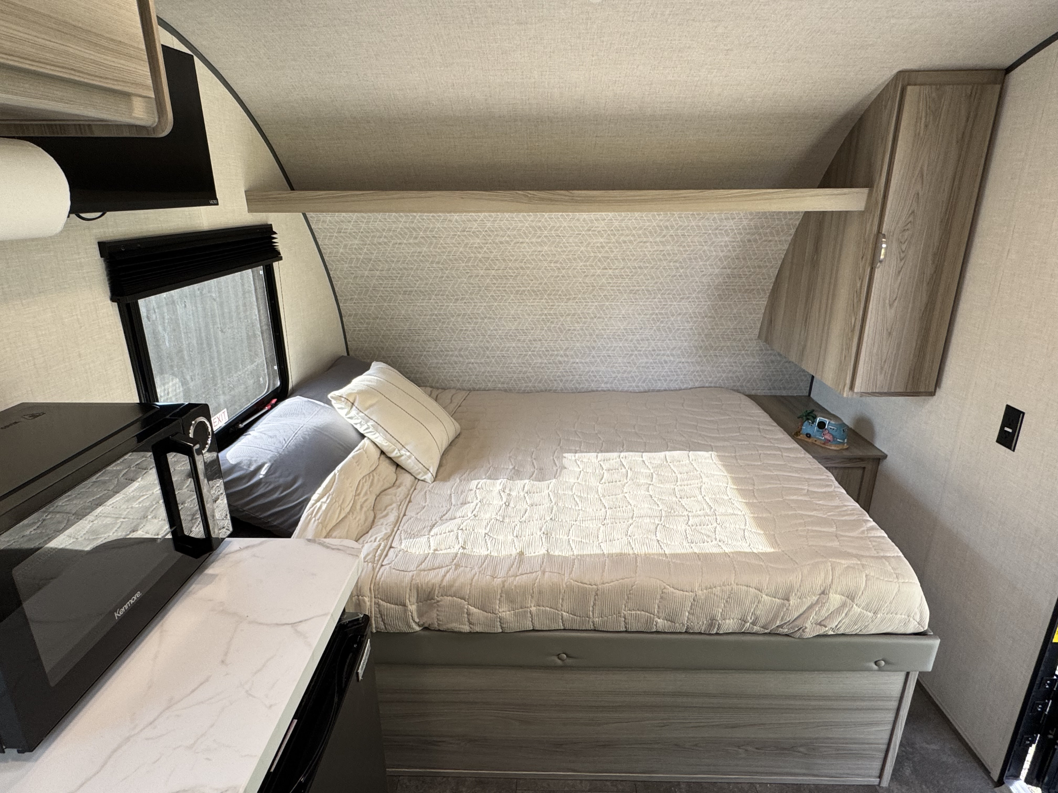 Cozy RV rental bedroom features a comfortable bed, overhead storage, and a handy microwave.. Forest River Wildwood FSX Platinum 2025