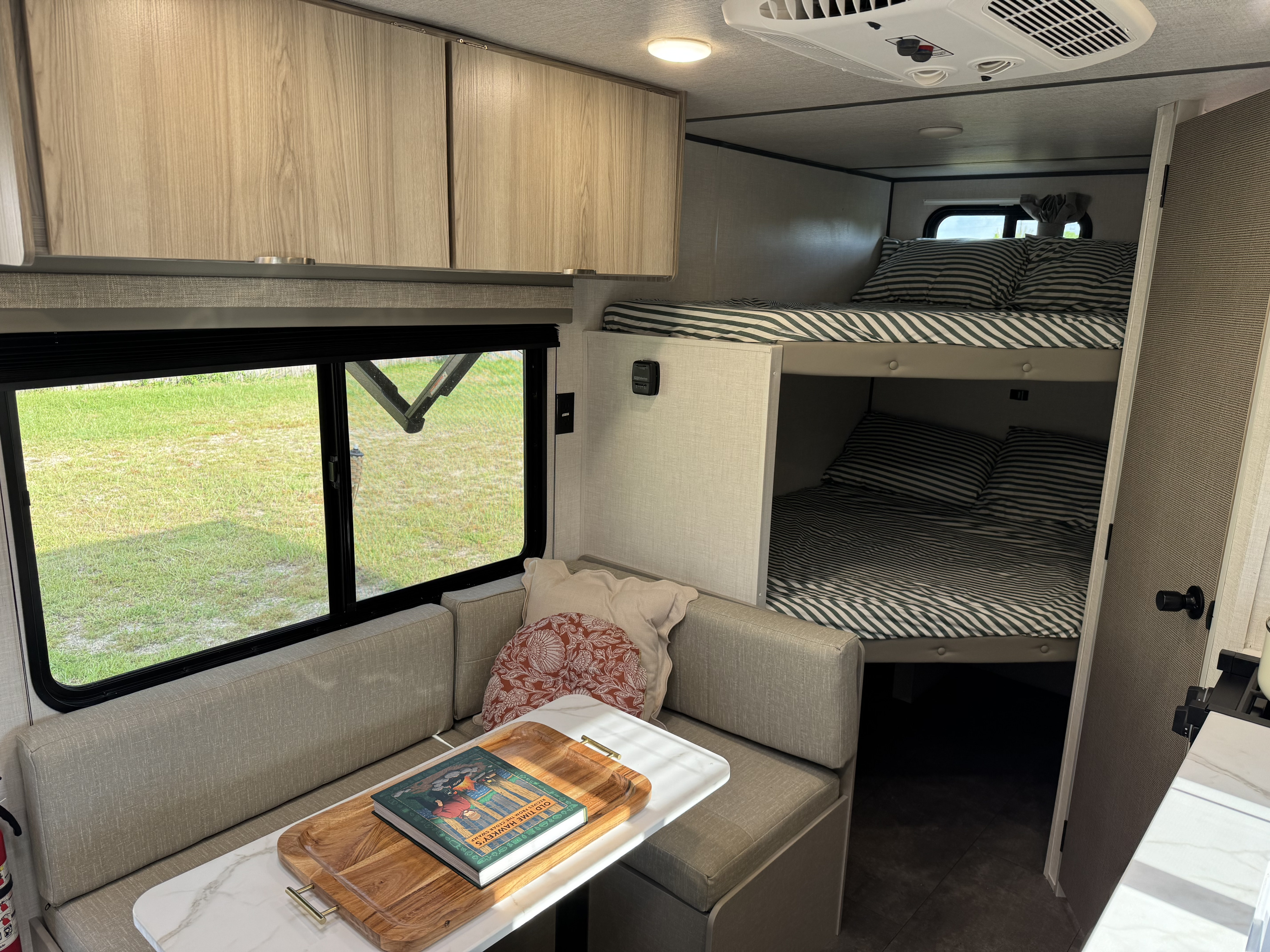 Cozy RV rental interior with dinette, large window, and comfy bunk beds. Ideal for family trips.. Forest River Wildwood FSX Platinum 2025