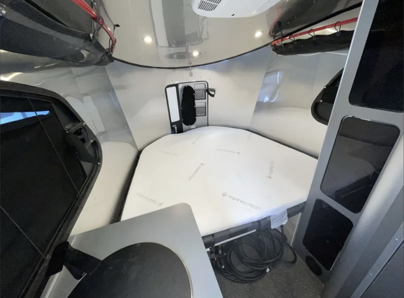 Cozy RV rental interior: A bed with an organic cotton mattress, compact kitchenette, and storage provide comfortable travel accommodations.. Ford/Airstream Basecamp/15 Seat passenger van 2024