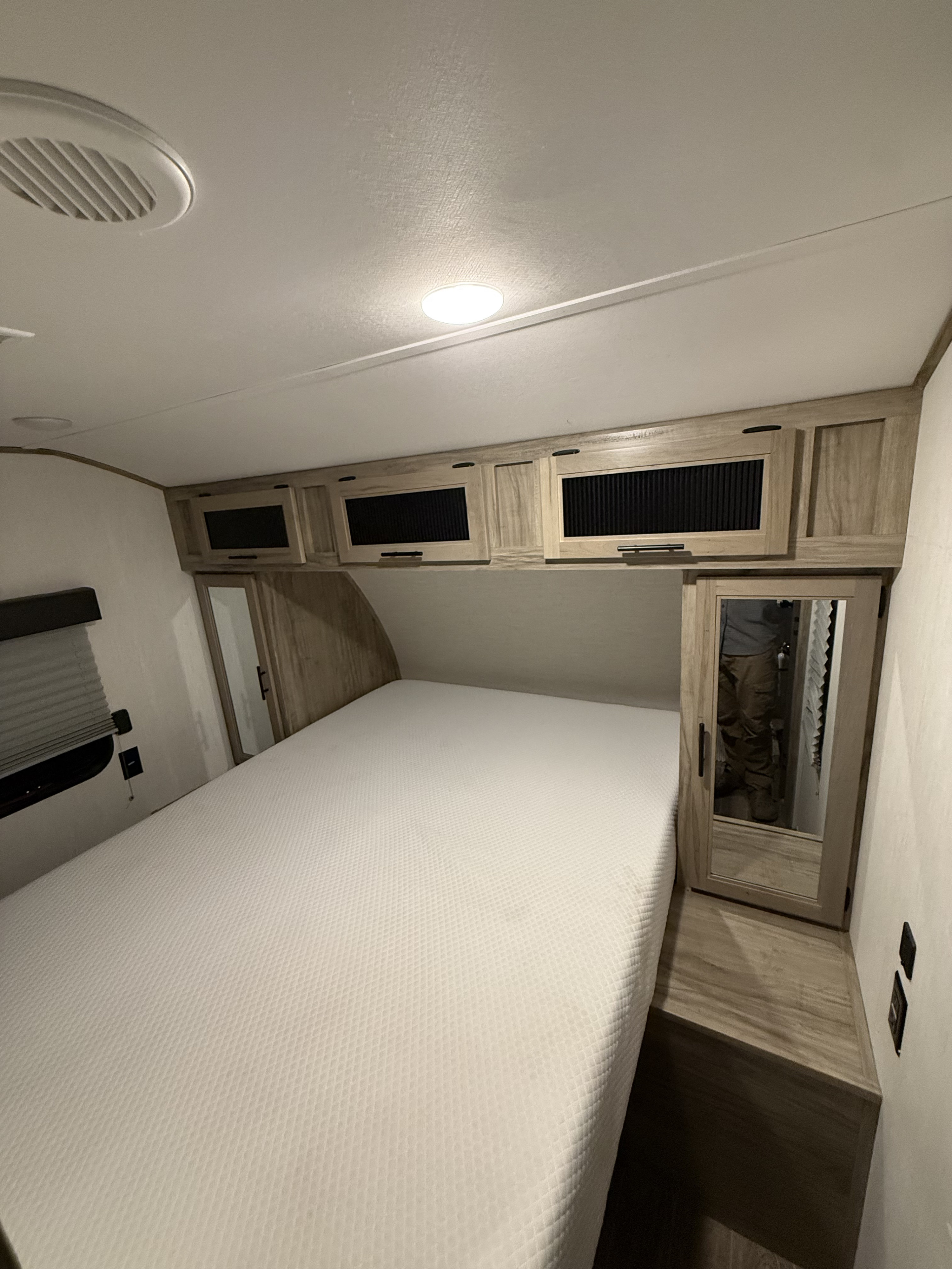 Inside an RV rental bedroom: A comfortable bed, overhead storage, and modern lighting, showing compact travel living.. Forest River Cherokee Alpha Wolf 2022