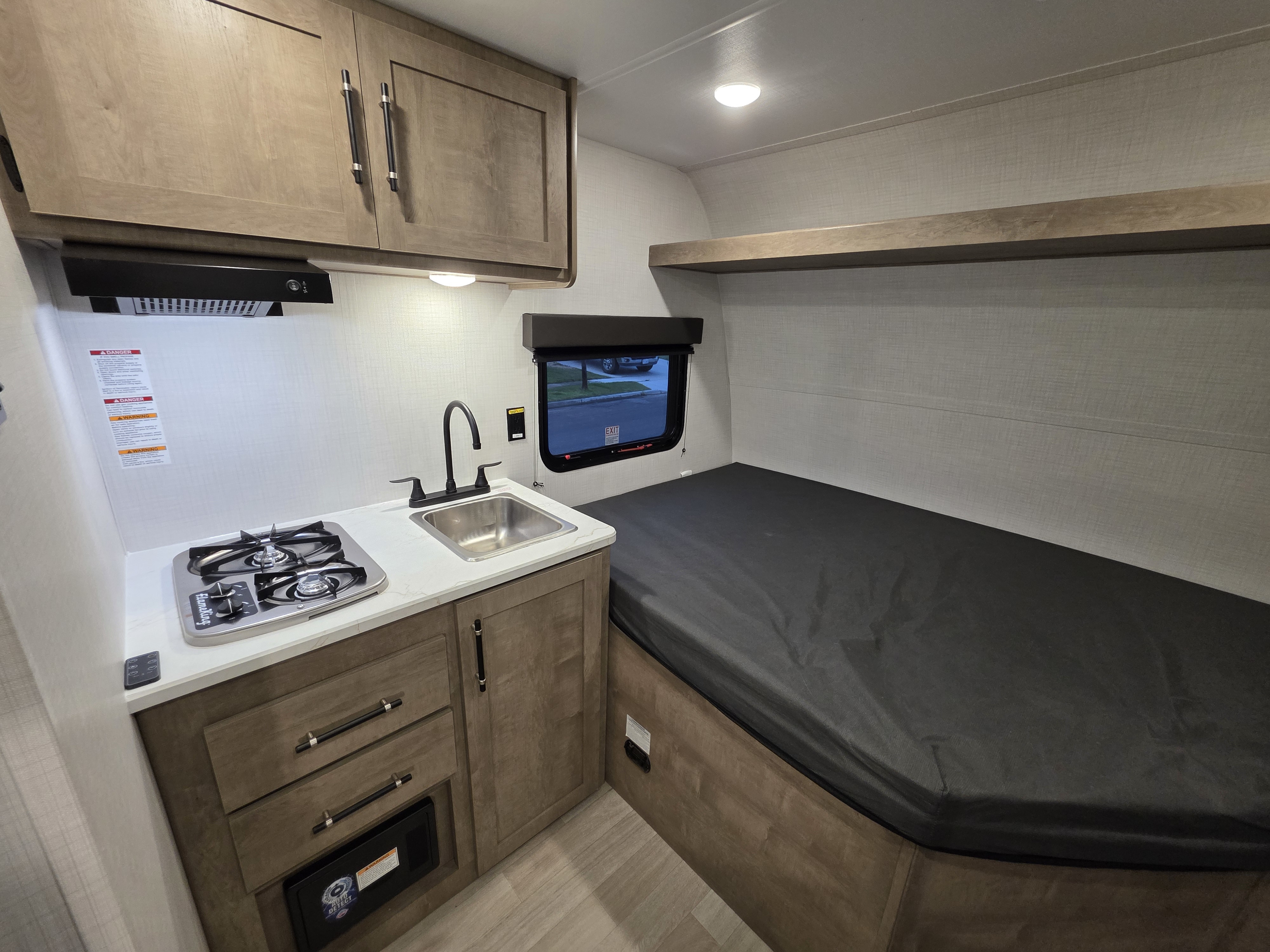 This RV rental offers a compact interior with a kitchen area featuring a stove, sink, and cabinets, plus a comfortable bed.. Keystone Springdale 2026