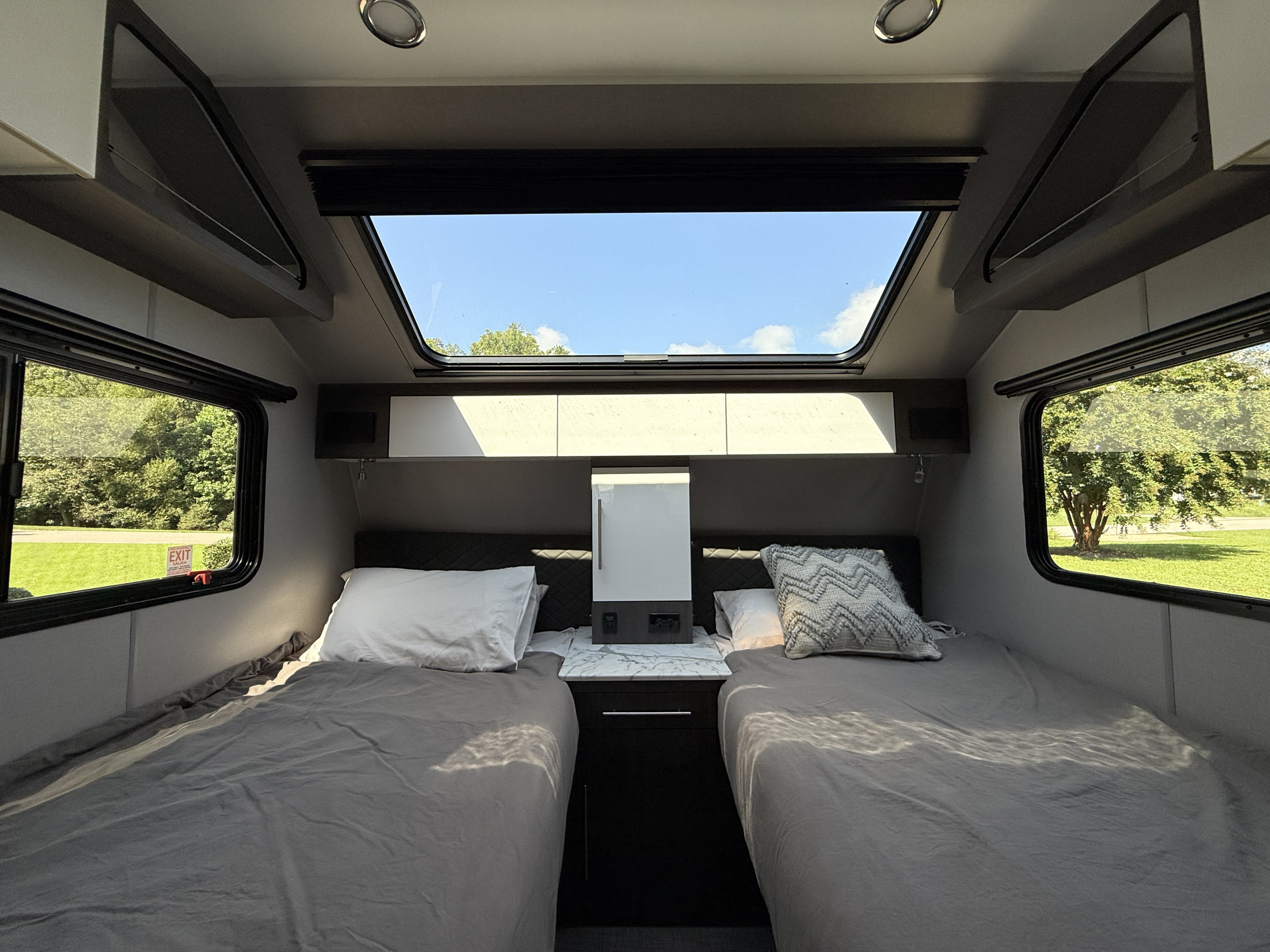 Bright RV rental bedroom with two twin beds, large skylight, and scenic window views for comfortable travel.. InTech RV O-V-R 2023