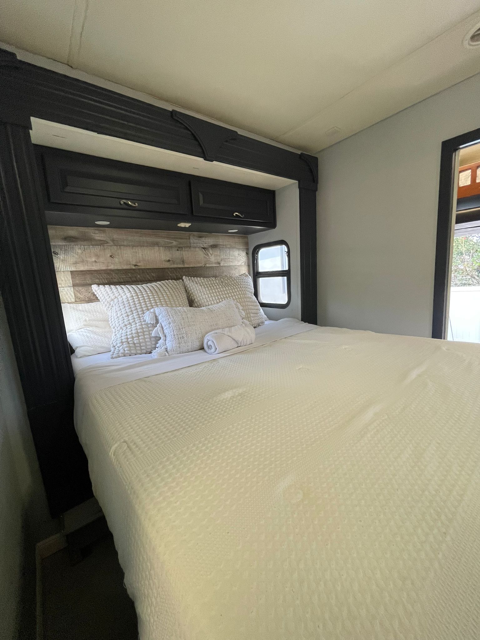Cozy RV rental bedroom with white bedding, wooden headboard, and overhead storage. Perfect for a comfortable stay.. Canyon Star Canyon Star Motorhome 2011